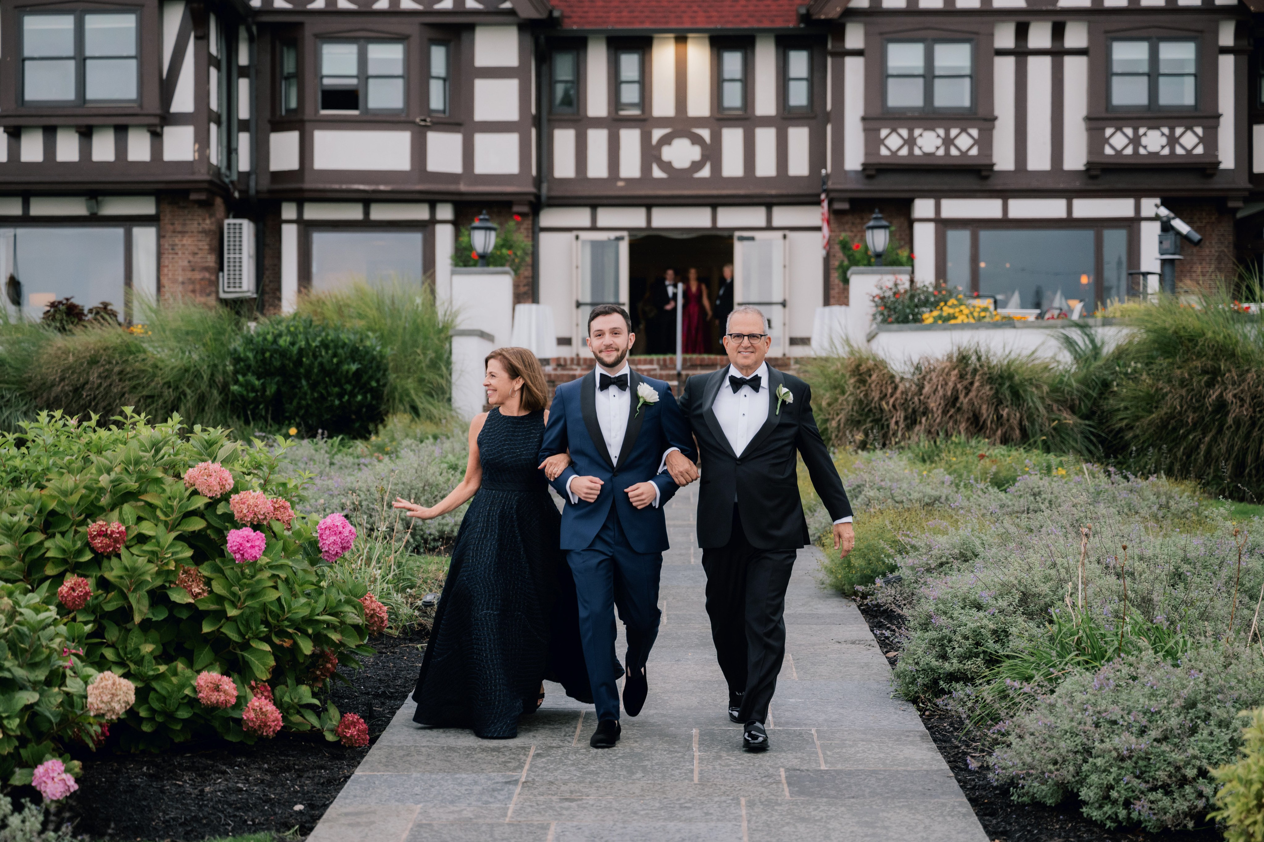 a bride and groom walking down a path in front of a house
