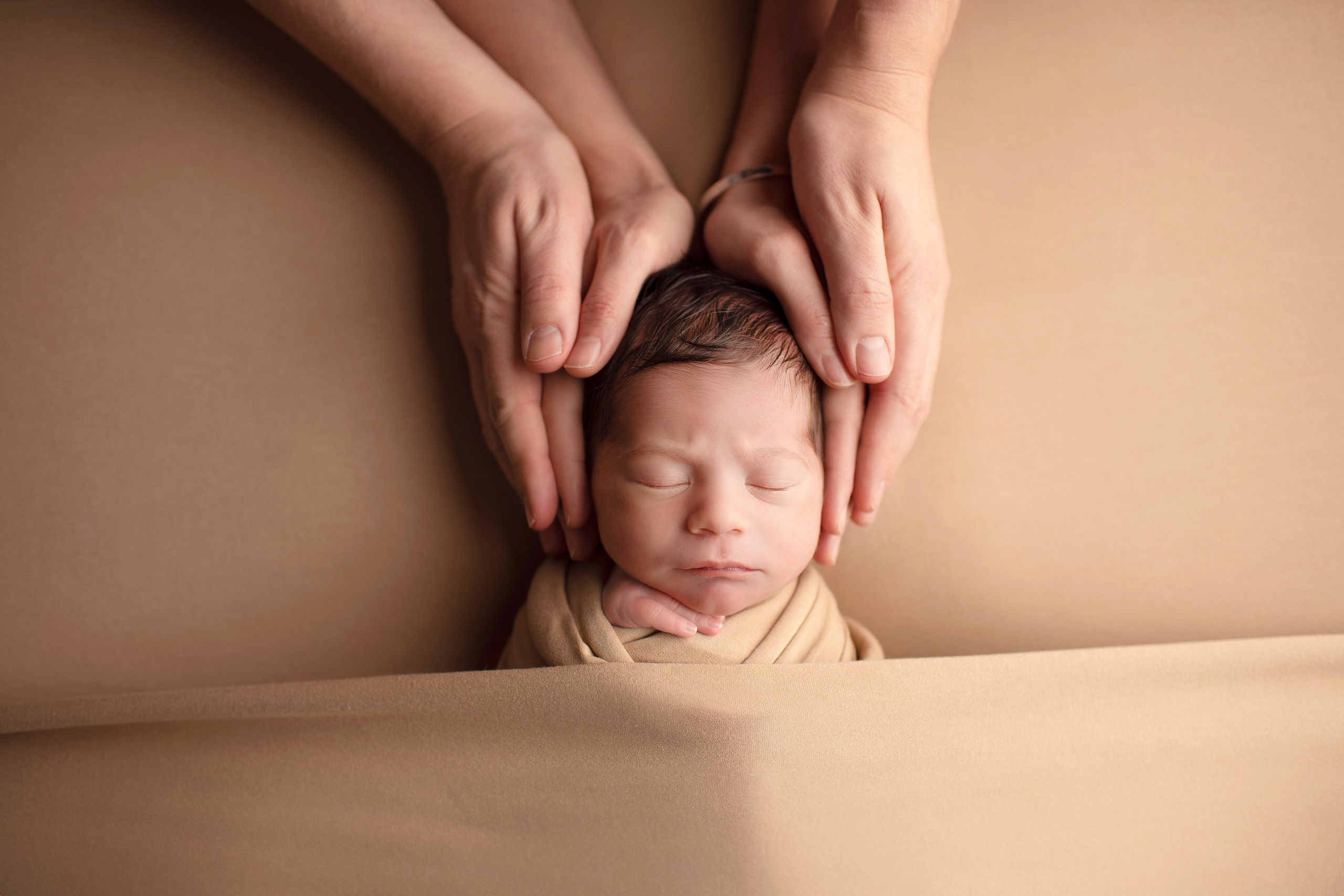 Söta ögonblick mellan en nyfödd baby och den stolta stora syskonet som sitter tillsammans i en mjuk filt. Bilden fångar den speciella bindningen mellan det nyfödda barnet och det äldre syskonet."