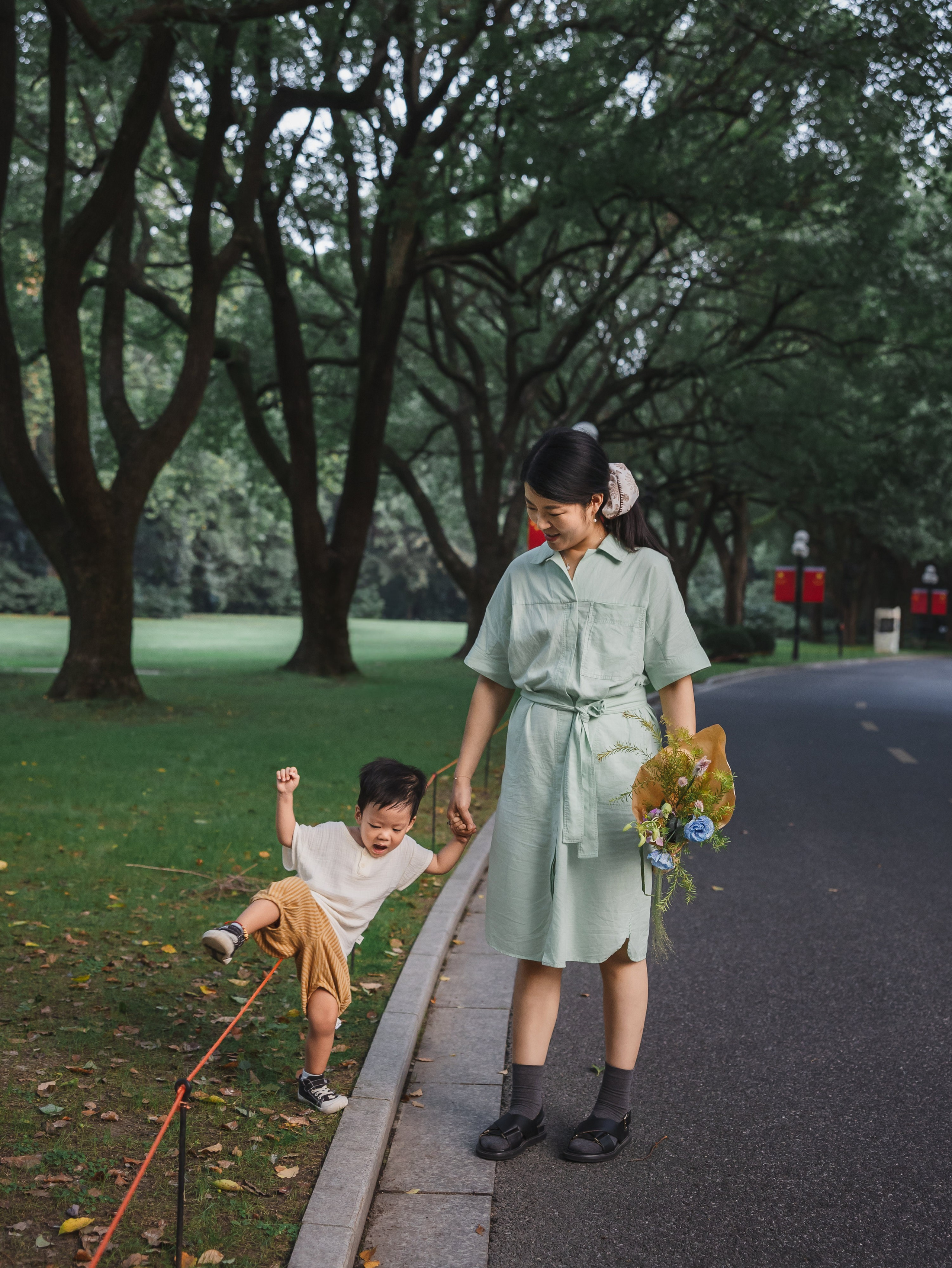Mom holds her child's hand near the park road as the session closes with a calm evening walk.