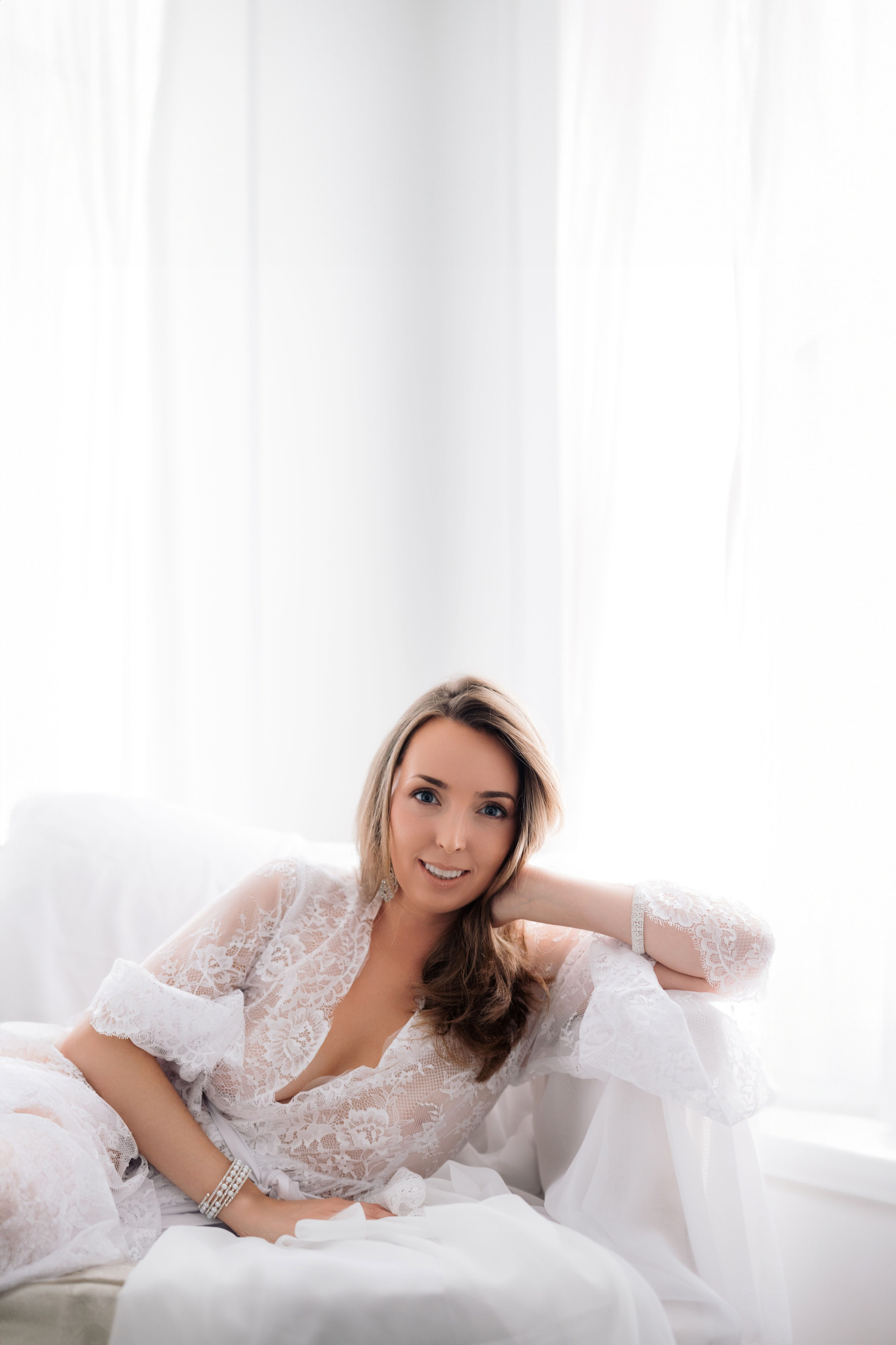 a woman in a white dress sitting on a bed