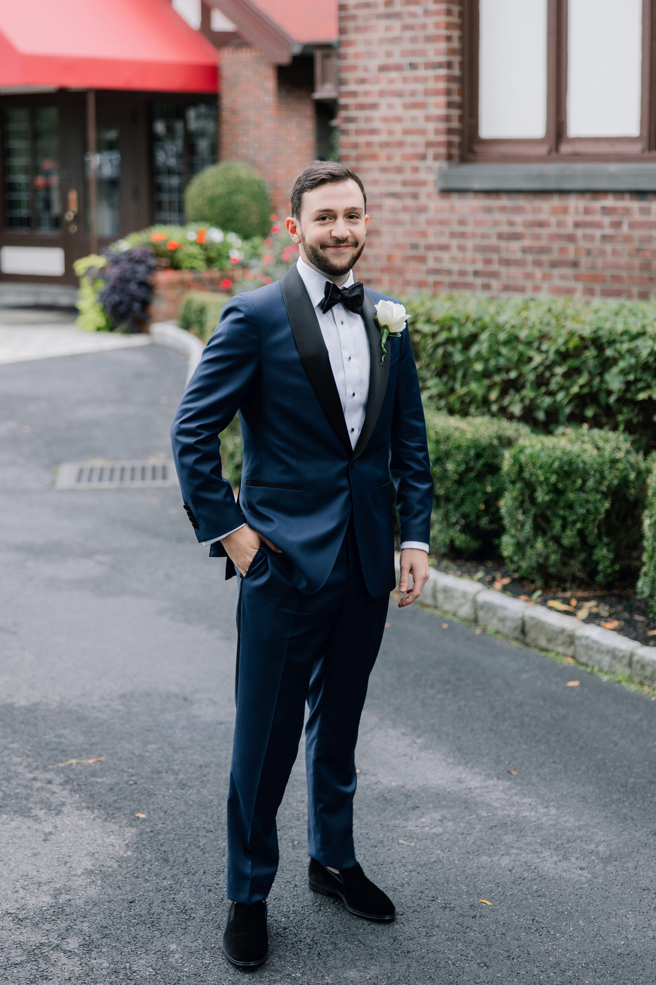 a man in a suit and bow tie standing in the street