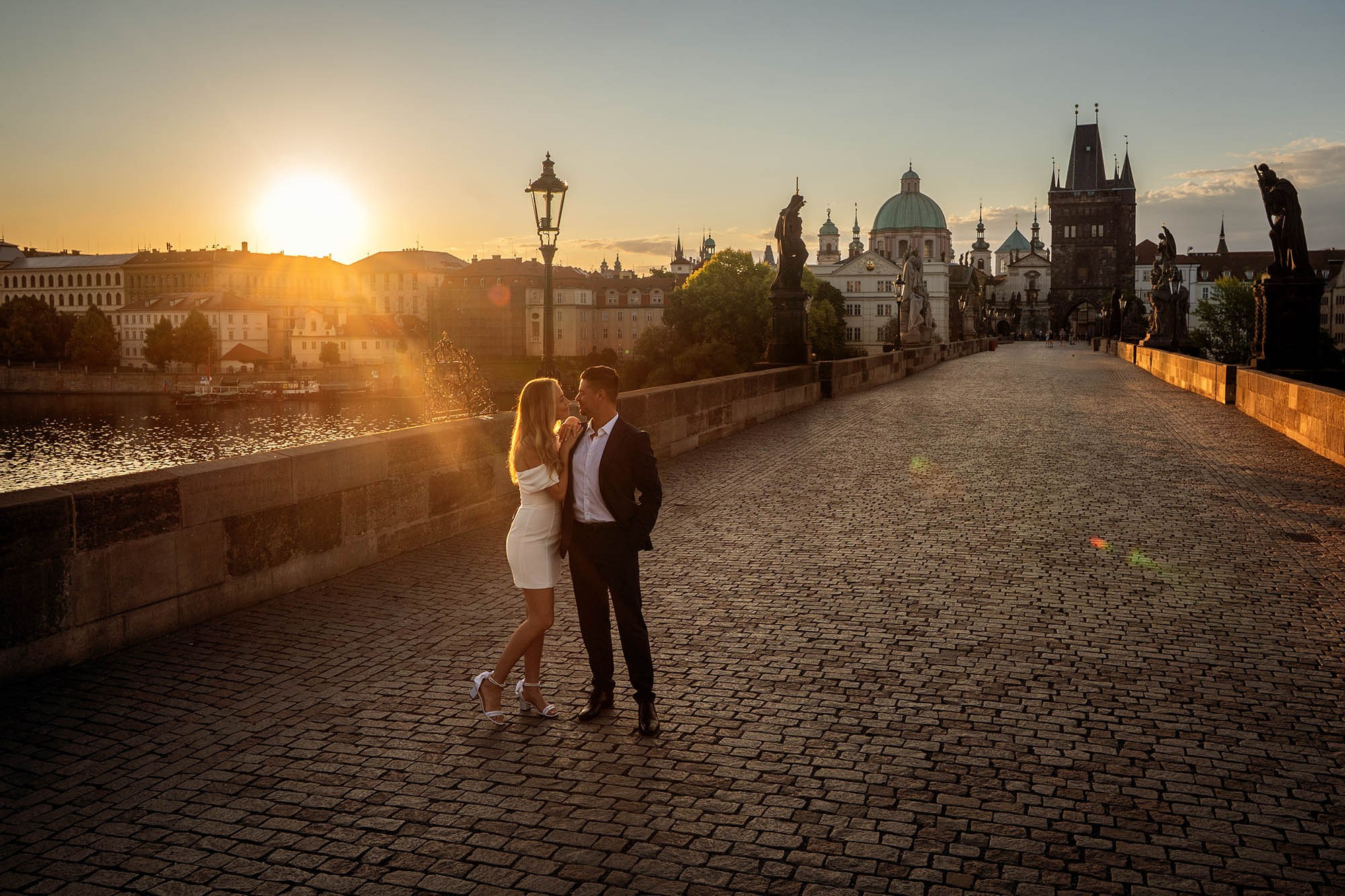 A loving California couple embracing in gentle sunrise warmth on the iconic Charles Bridge.