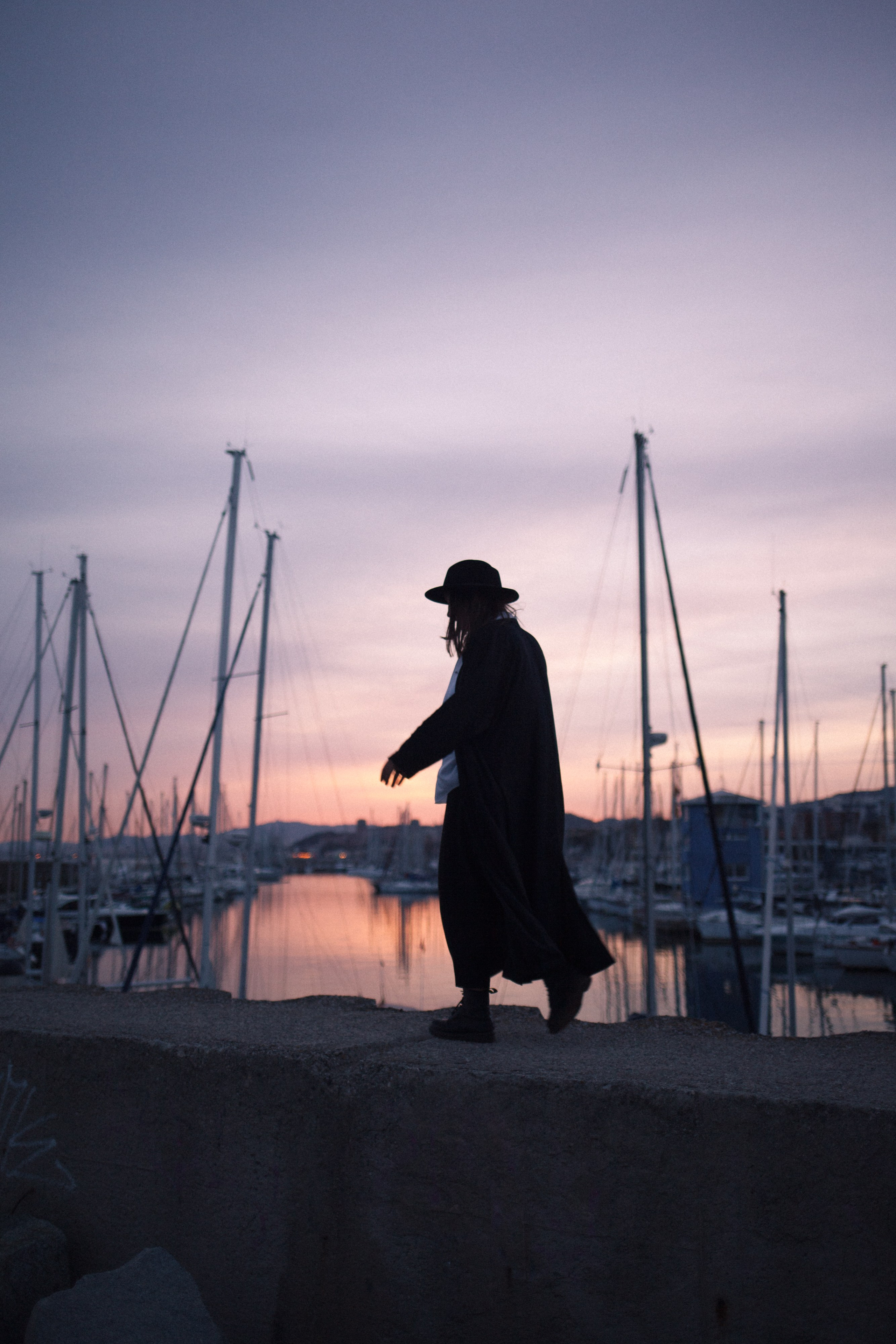 Portrait of a person walking through the port of El Masnou by the sea at sunset