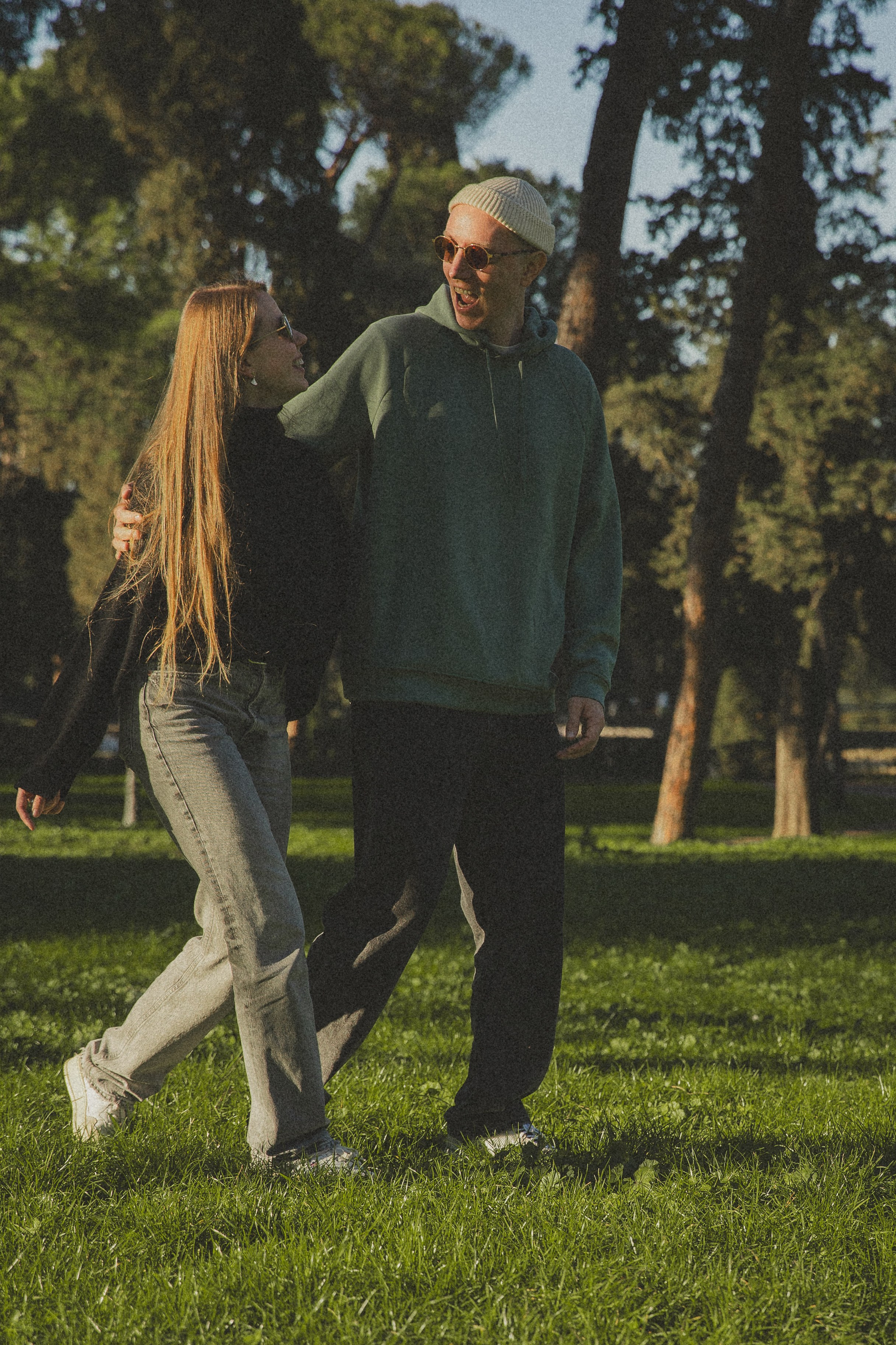 A candid photograph of a couple walking in Villa Borghese park in Rome, their expressions full of joy.