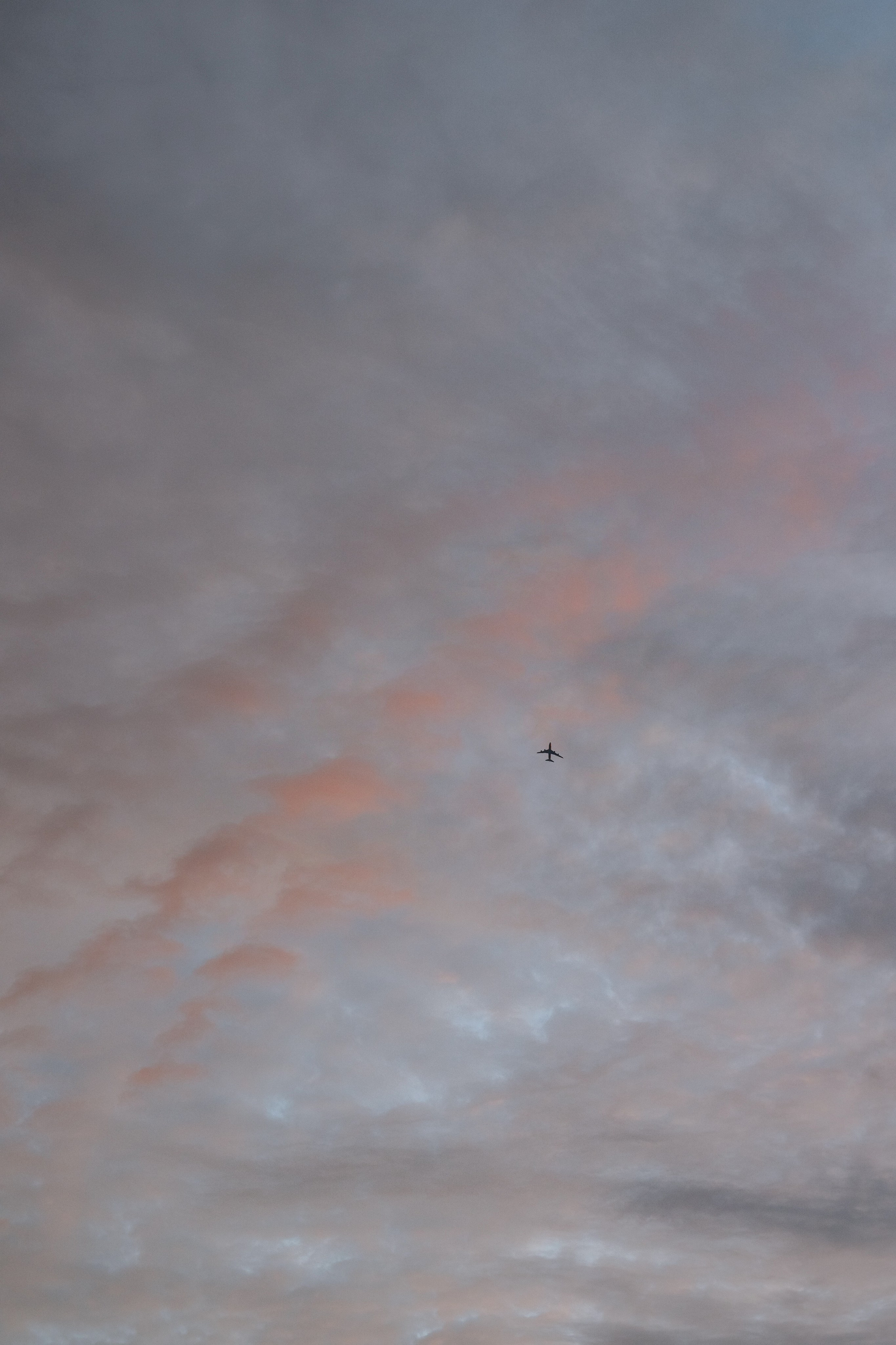 a plane flying in the sky at sunset