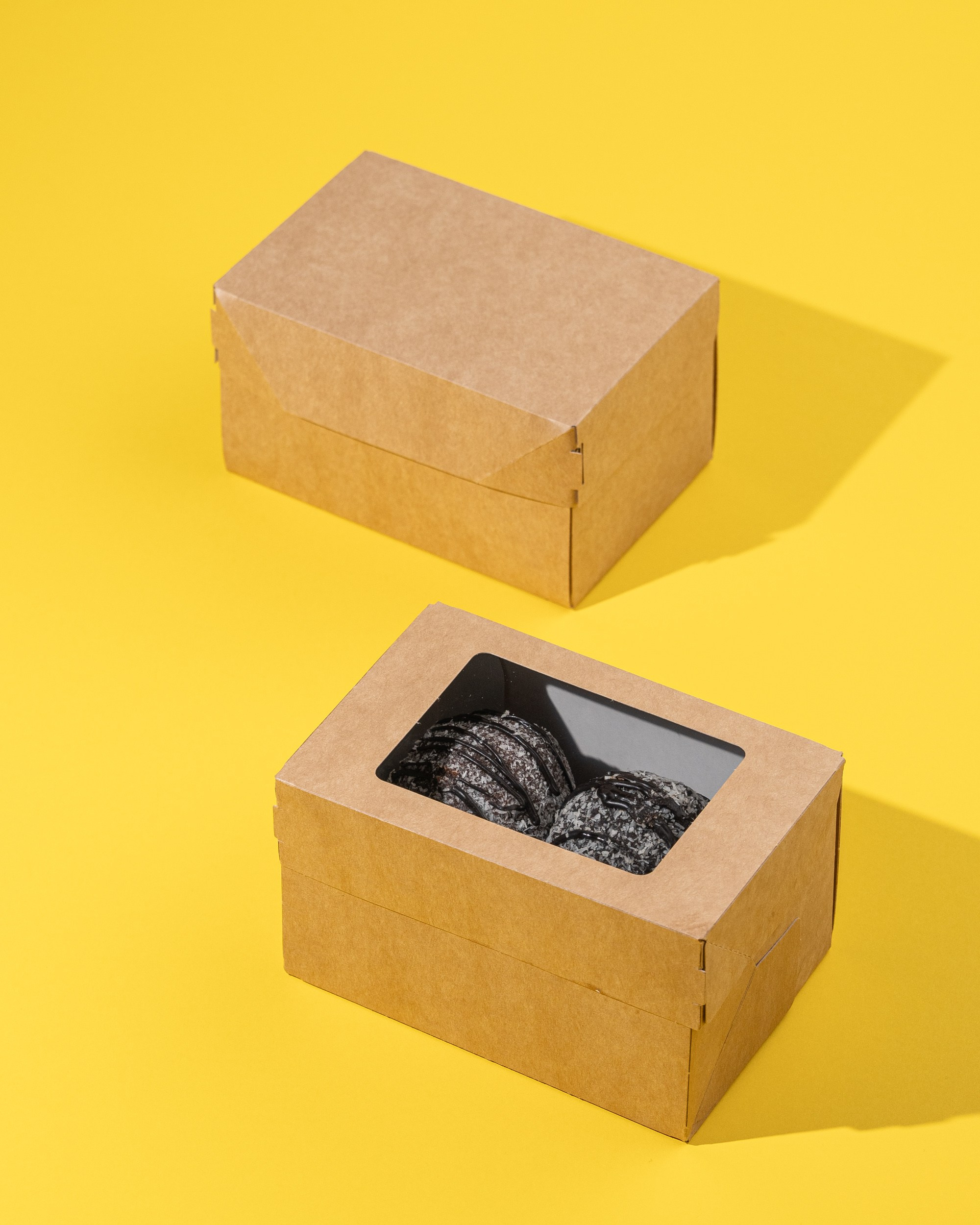 Sarı fon üzərində pəncərəli və pəncərəsiz karton şirniyyat qutuları, içində şokoladlı desertlər.