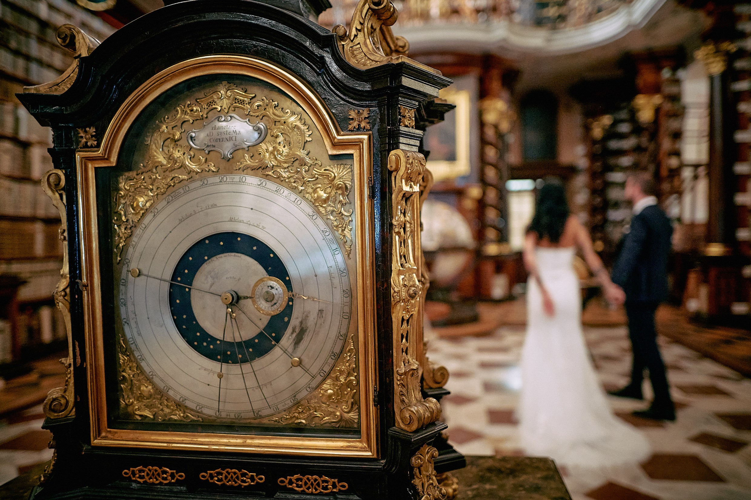Antique clock framing couple in exclusive Klementinum Library access.