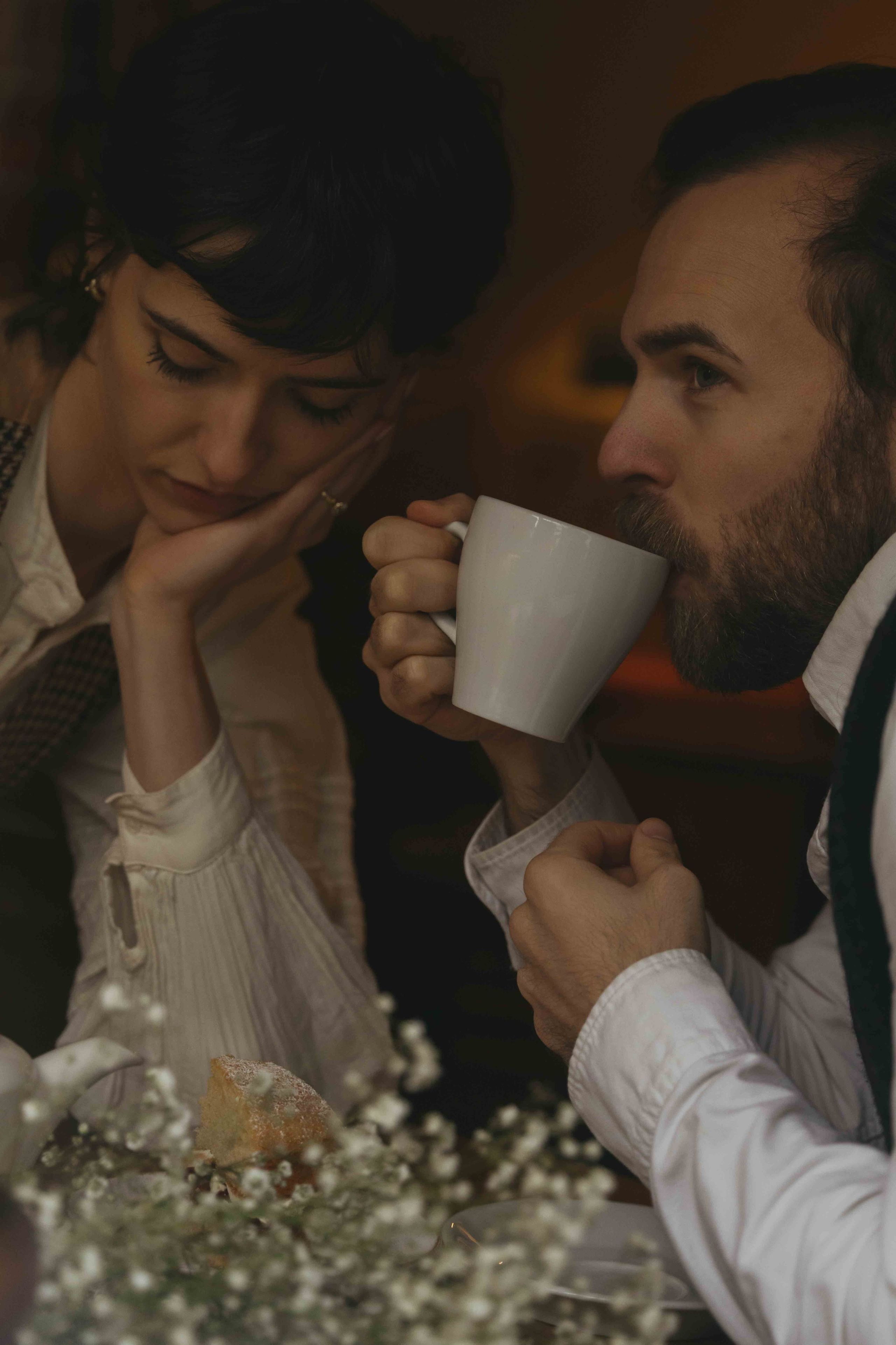 cinematic couple moment in pub with warm light and tea during rainy day photoshoot