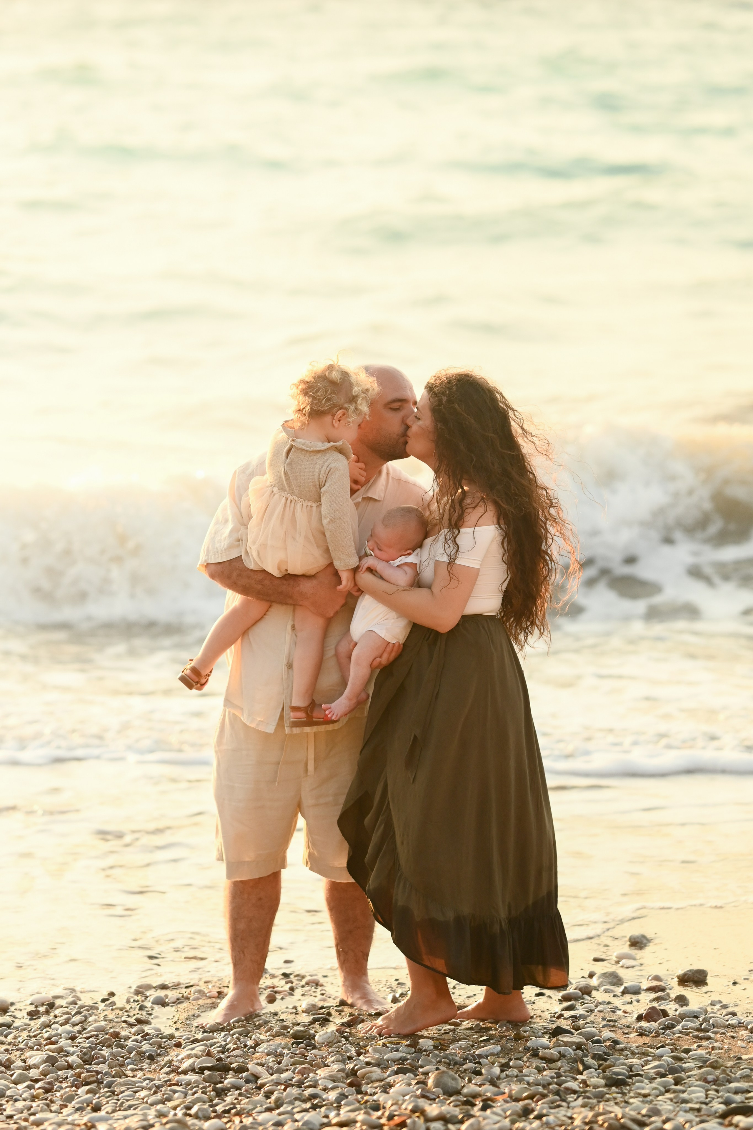 Happy family walking along a Rhodes beach at sunset. Photographer in Rhodes Island