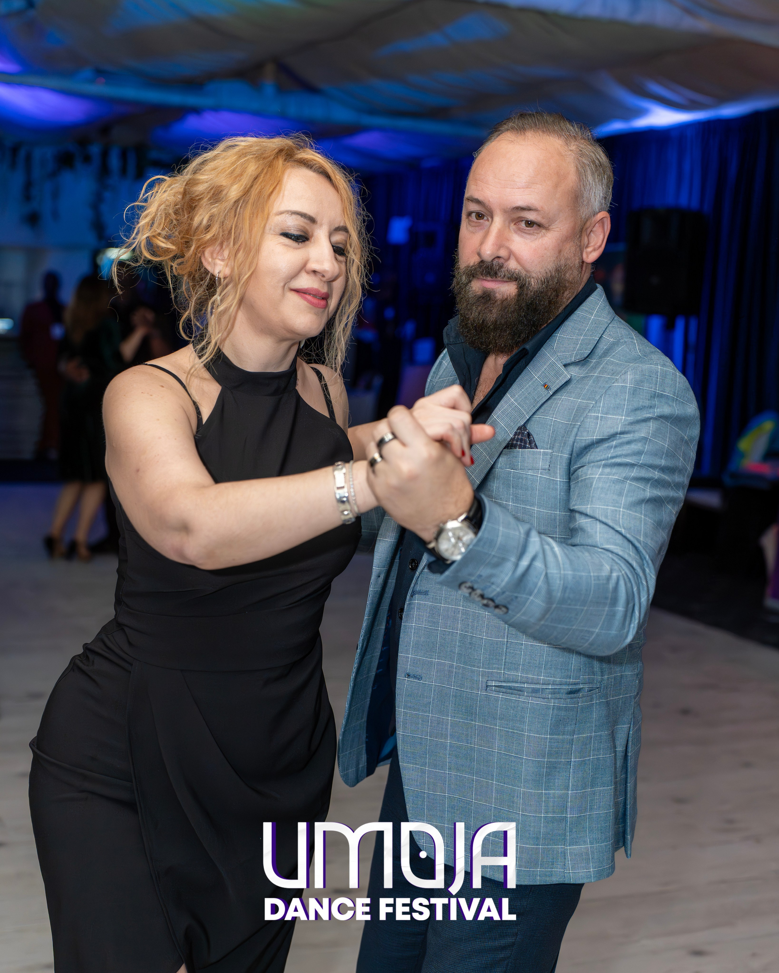 Man and woman dancing together at a dance festival with blue lighting background.