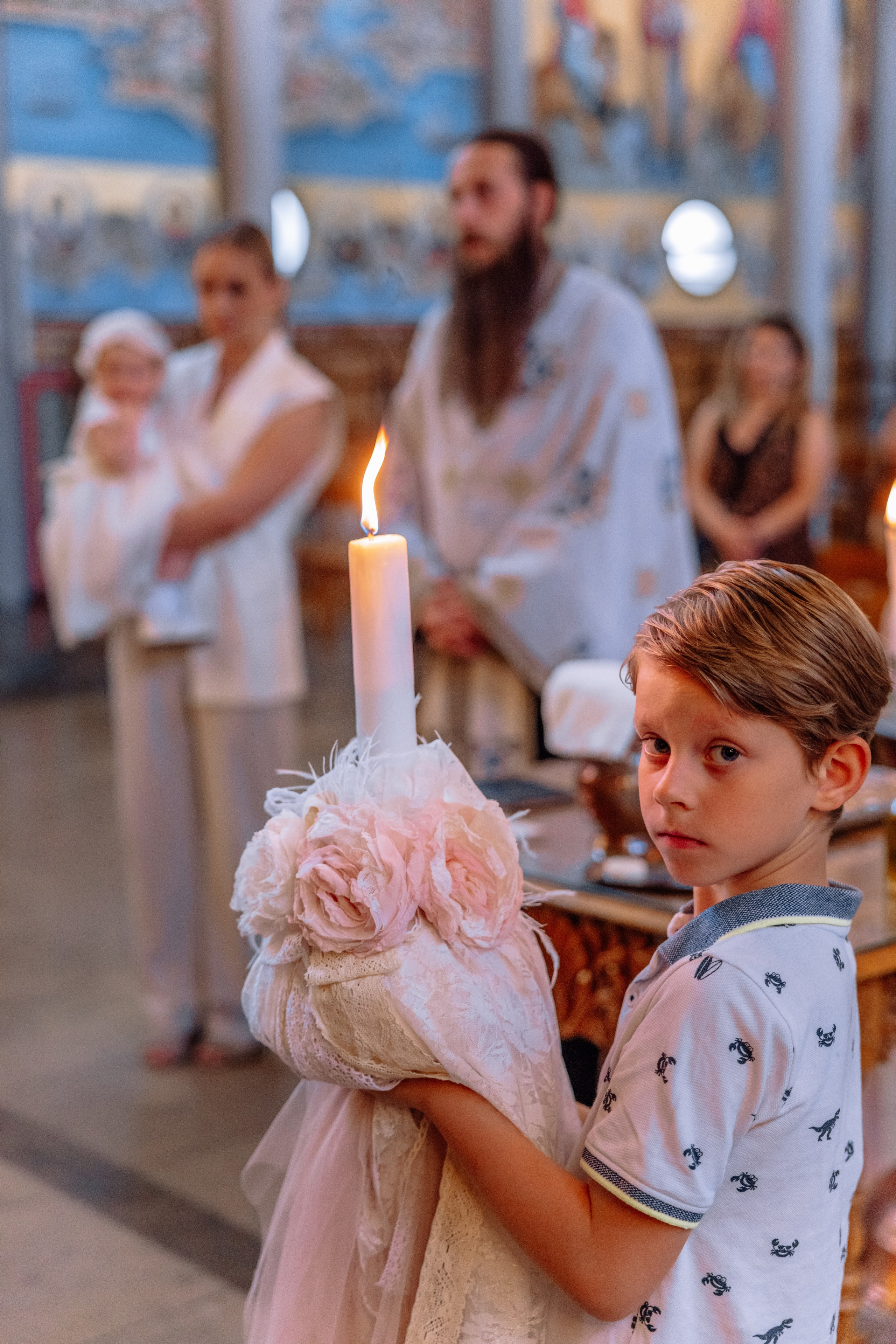 Das Kind hält Taufkerze – griechische orthodoxe Taufe München