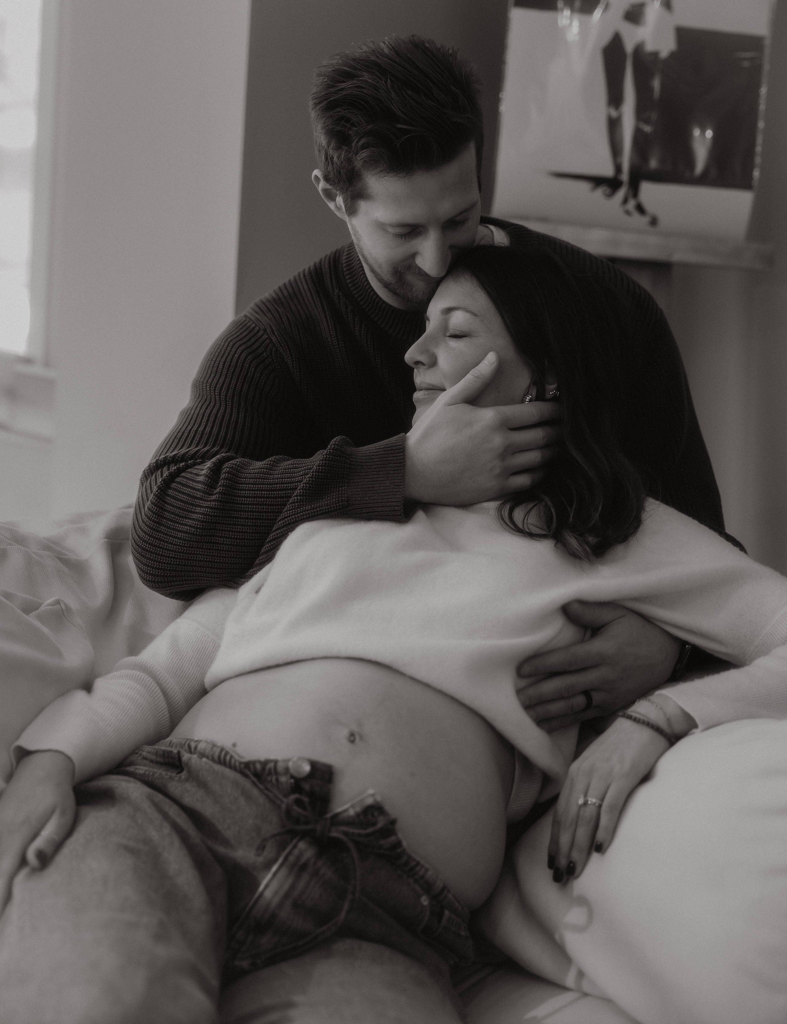 Expecting mama sitting in natural light studio with delicate floral styling