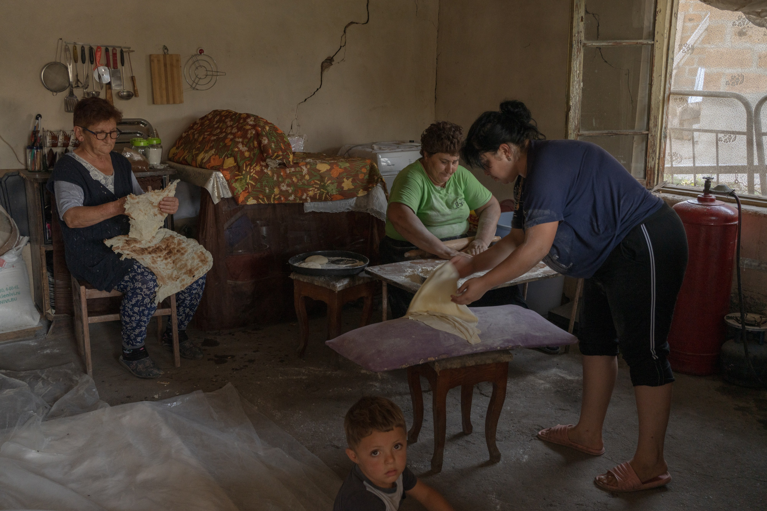 Baking lavash - an Armenian traditional thin bread - is a labor-intensive process. Often neighbors come in to keep the company and sometimes help out with children while women are busy baking. Bagaran, Armenia.