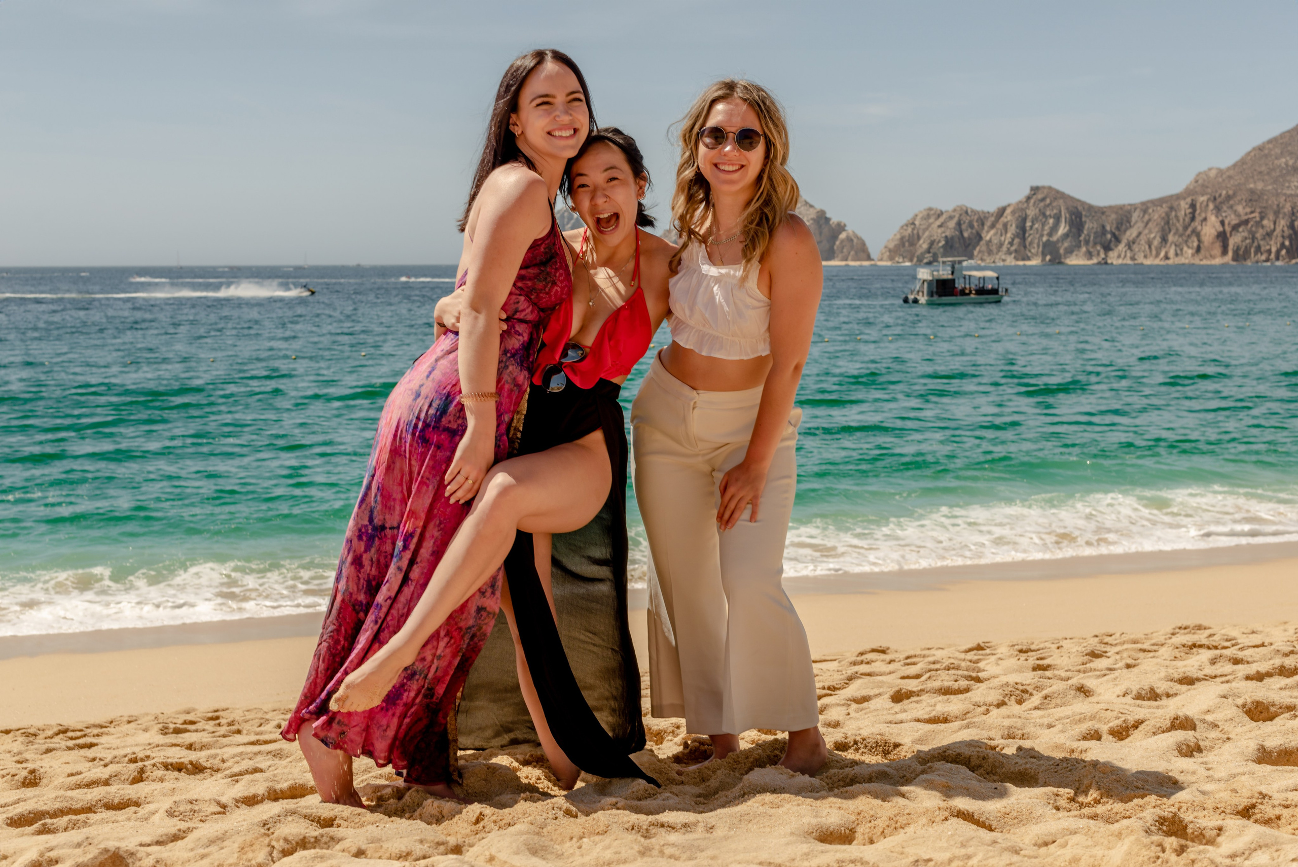 three women in colorful dresses during lifestyle portrait session on rocky beach in Los Cabos