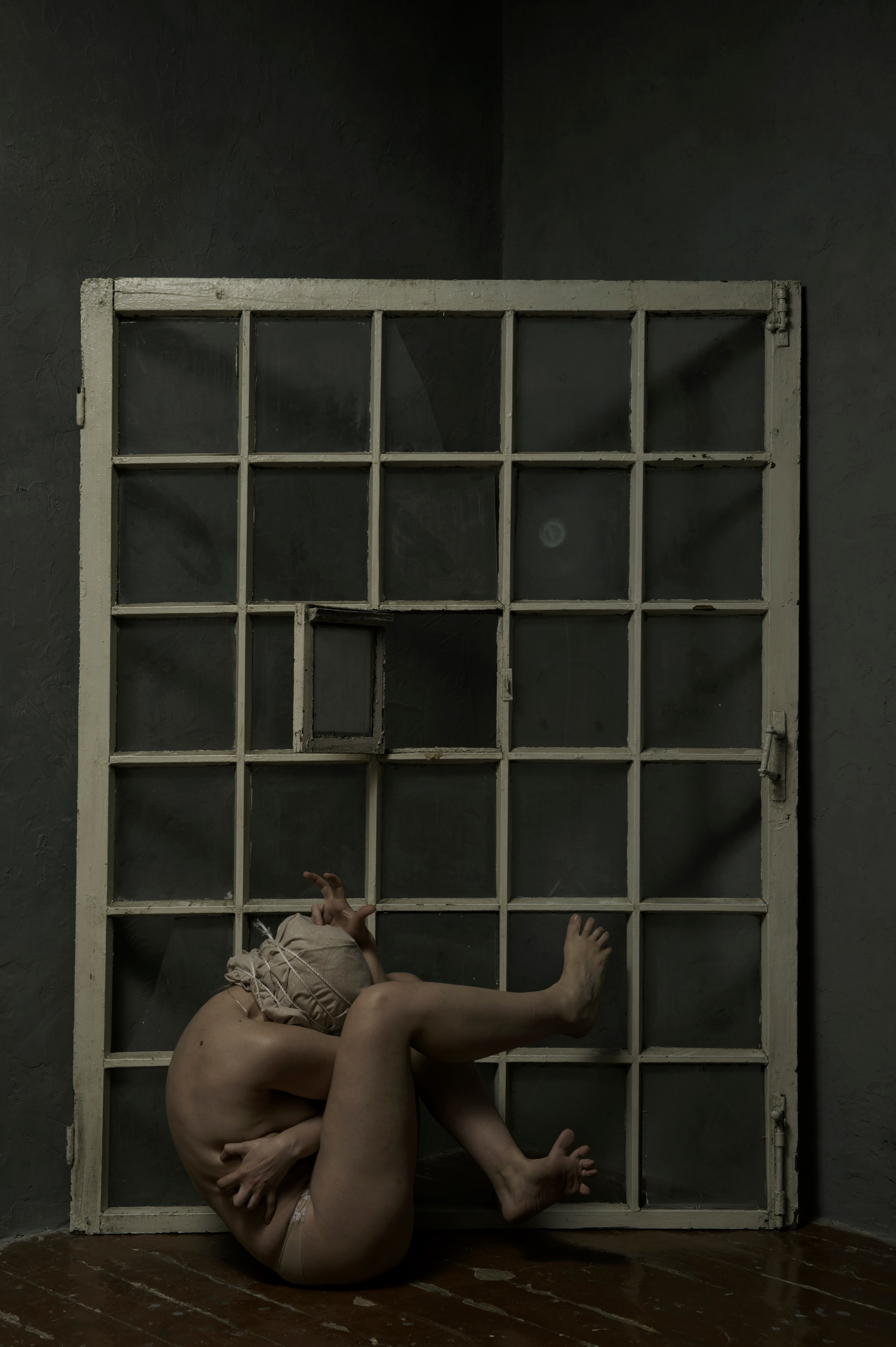 Dramatic photograph of a nude female figure with a concealed face, enveloped in deep shadows and rich tones, featured in Leni Smoragdova's 'Figures Collection: Dark Version' (2019).