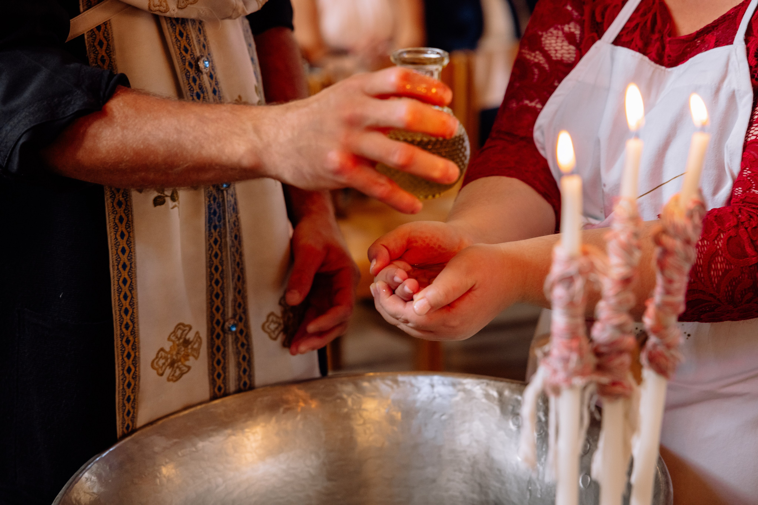 Priester gießt heiliges Öl auf die Hände des Babys – orthodoxe Taufe