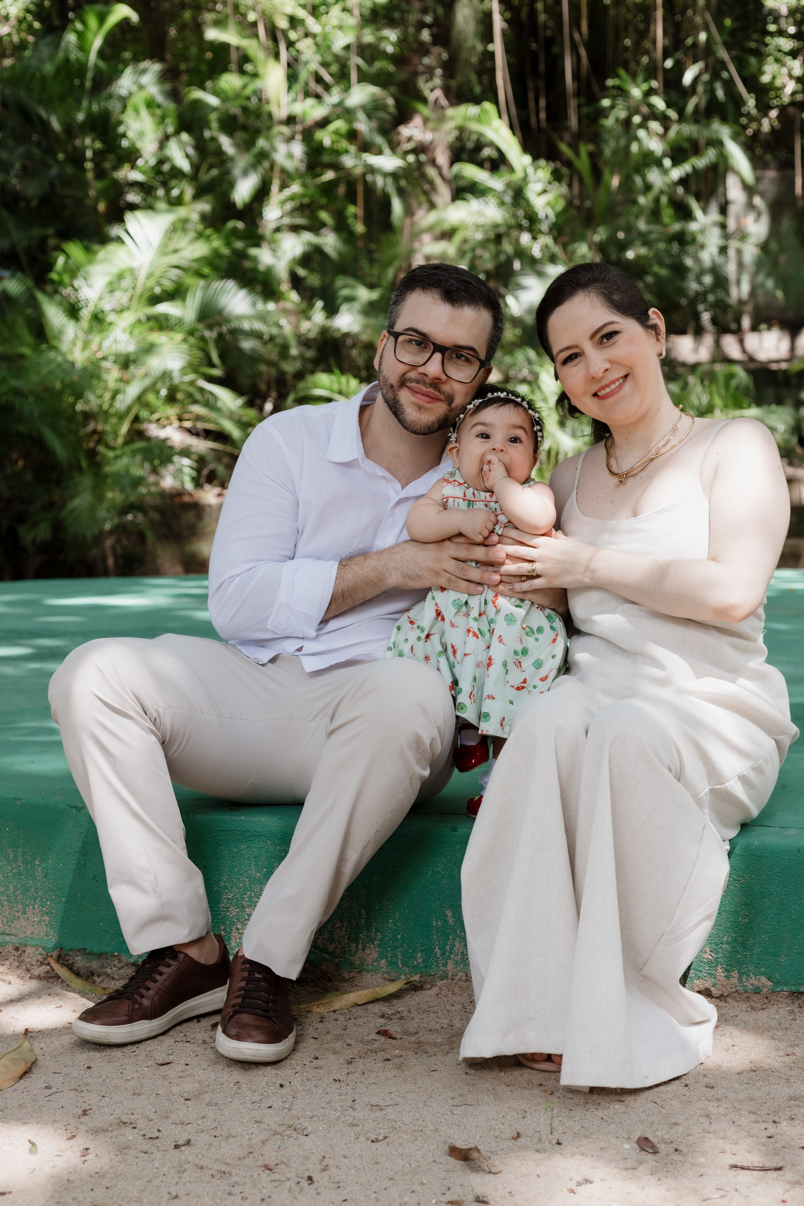 Pais com a bebê ao ar livre após o batizado