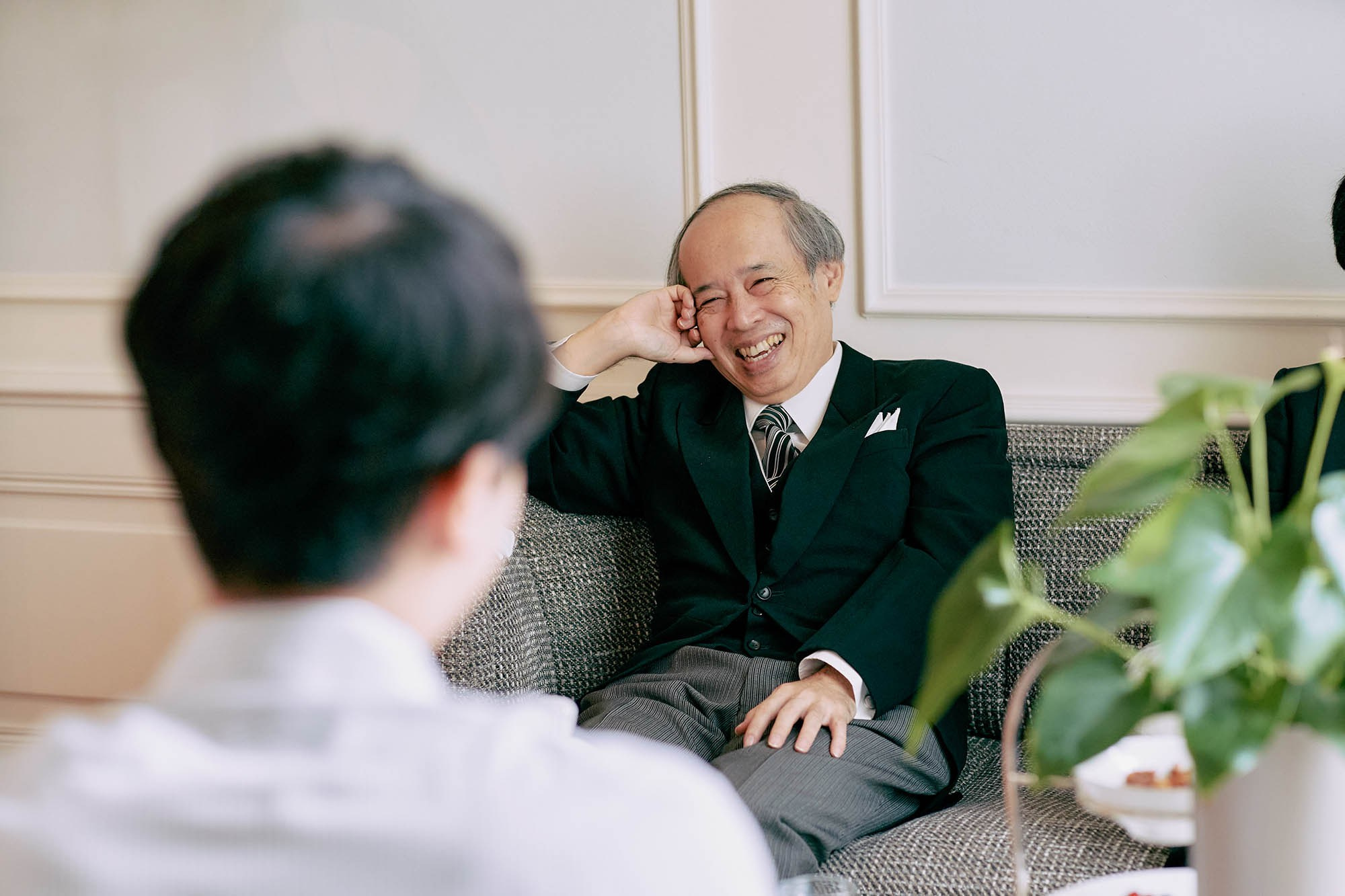 Katsuya's father share a laugh with the young groom as he awaits his bride's preparation in their suite.