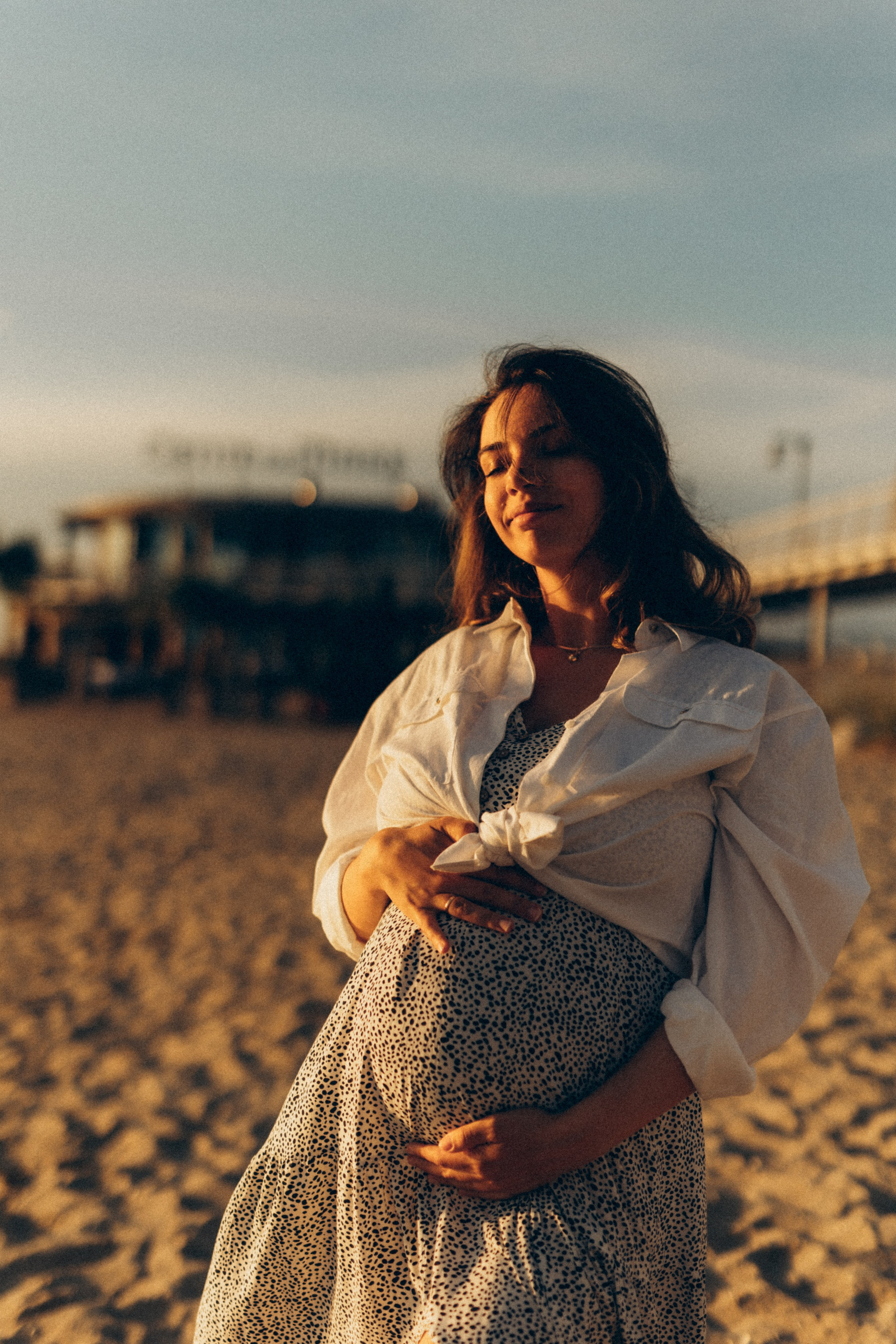 Ritratto di una donna incinta sulla spiaggia nella luce morbida della sera