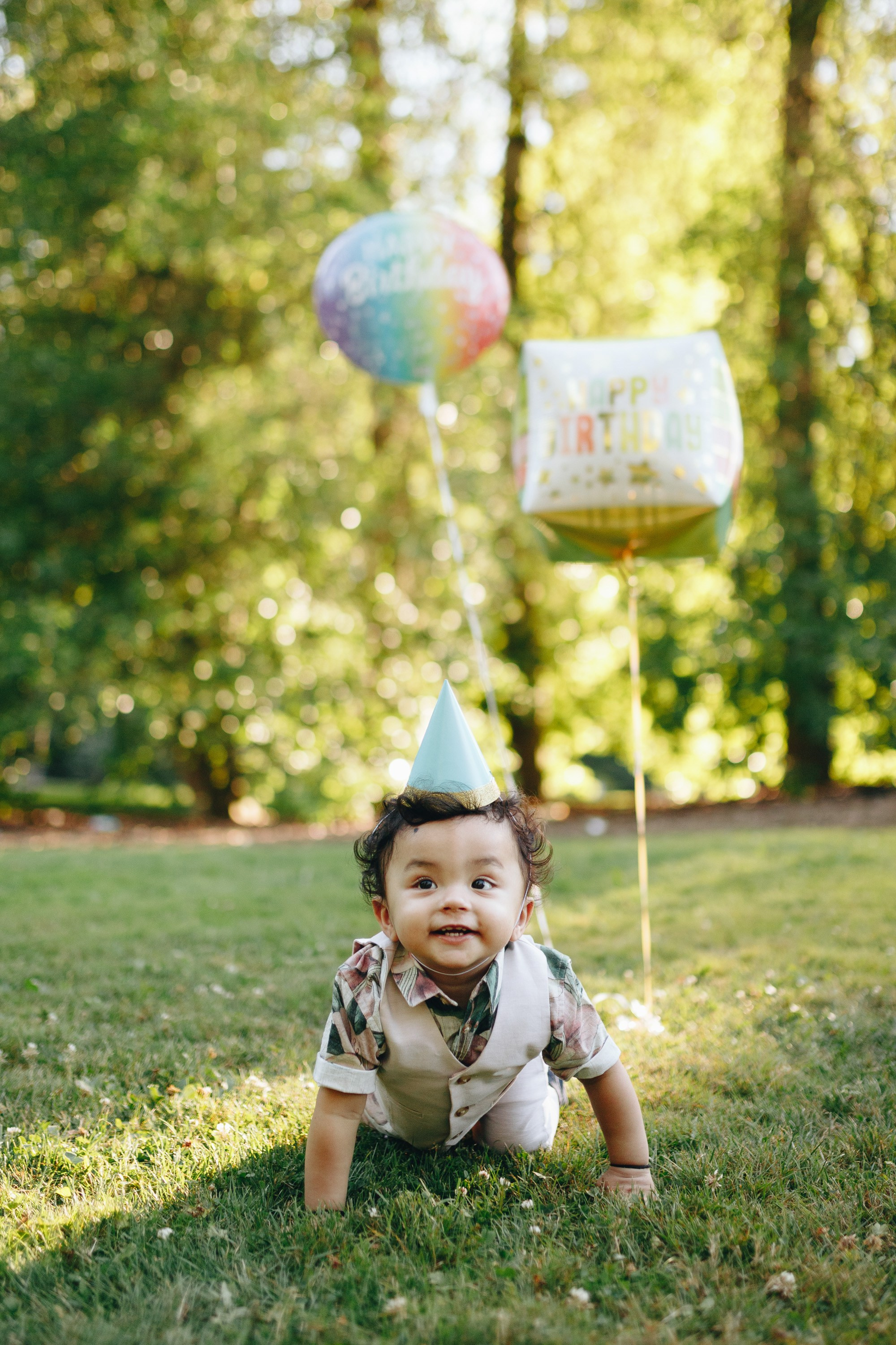 Baby crawling on grass with balloons behind