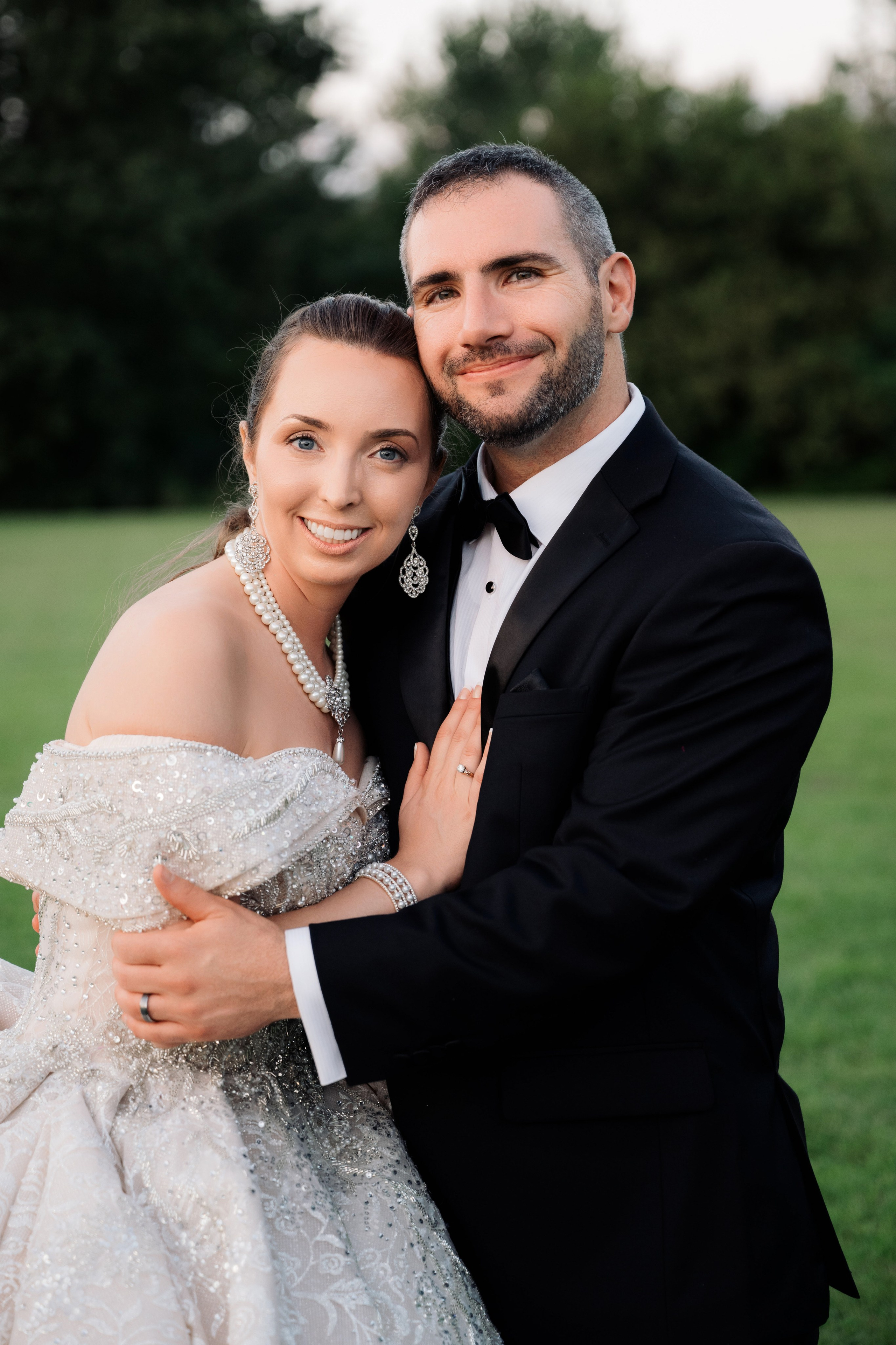a bride and groom pose for a photo in a field