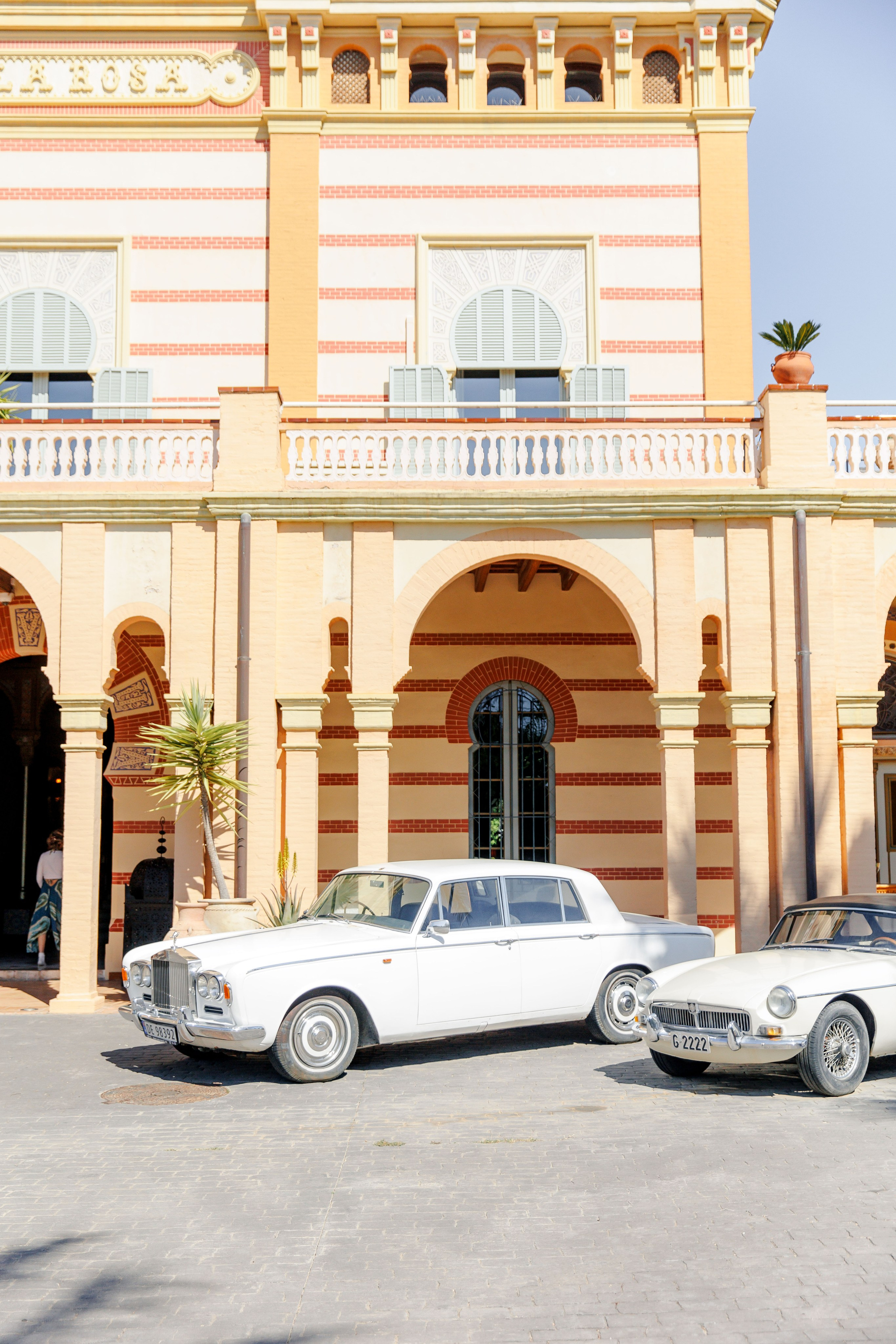 Two white old fashioned cars parked in front of the villa