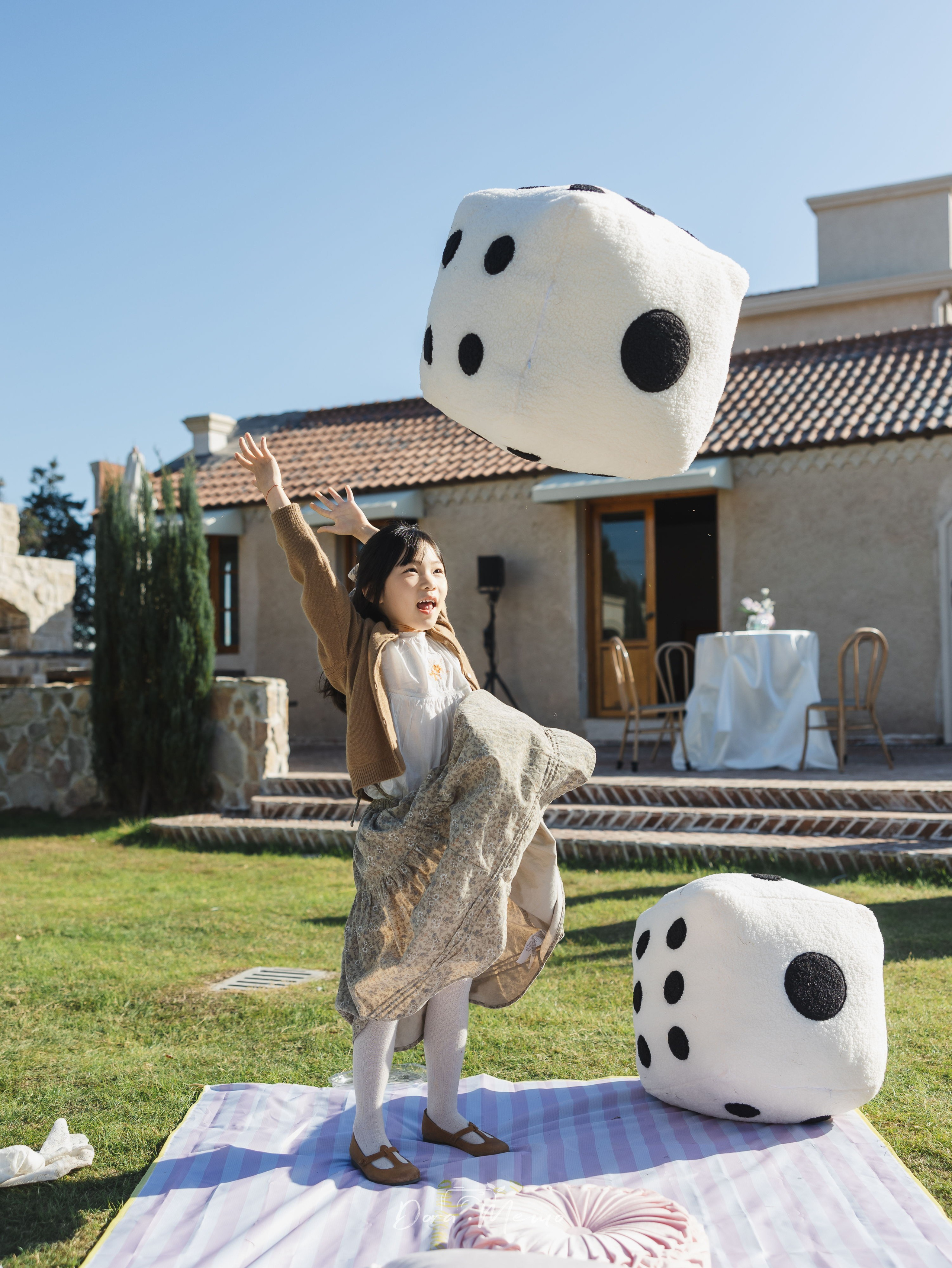 Child throwing large dice at outdoor birthday party, playful moment, documentary family session