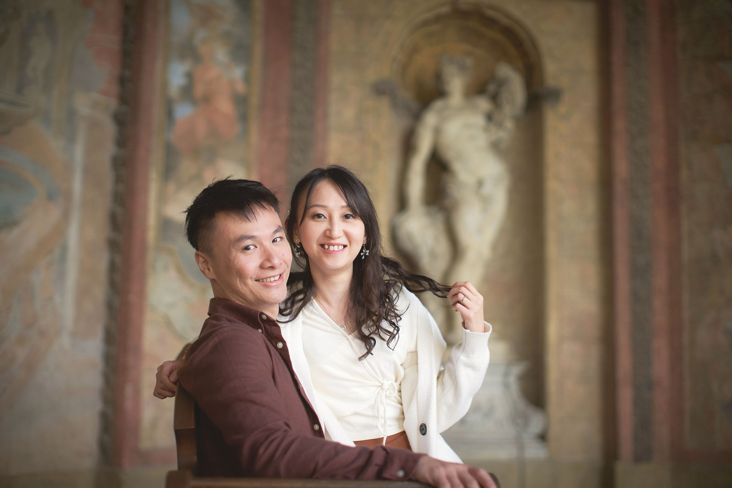 Eva and Conan are smiling at the camera while seated in Sala Terrena, Vrtba Garden.