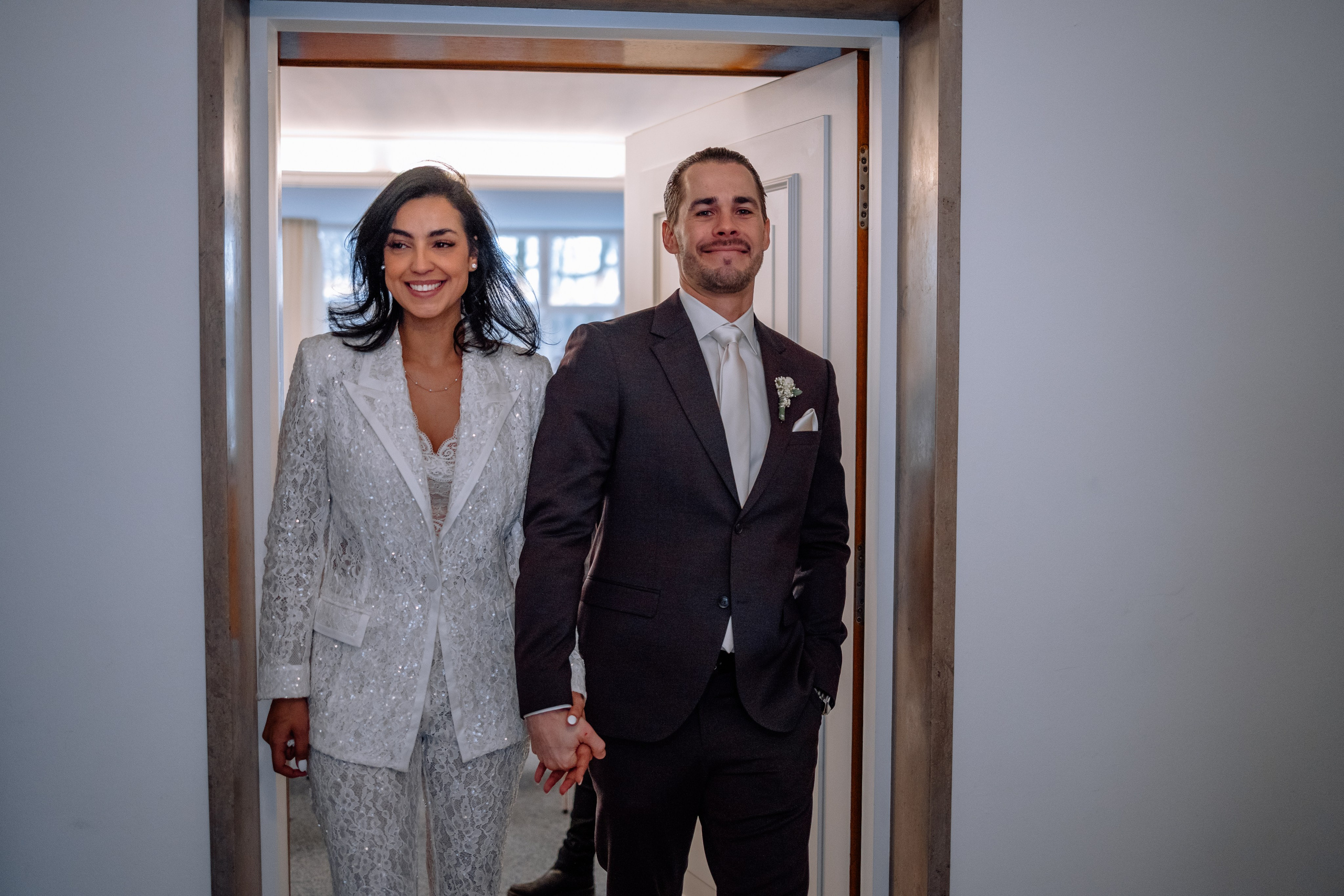 Braut und Bräutigam halten sich Hand in Hand – romantische Szene vor Standesamt Schwabing