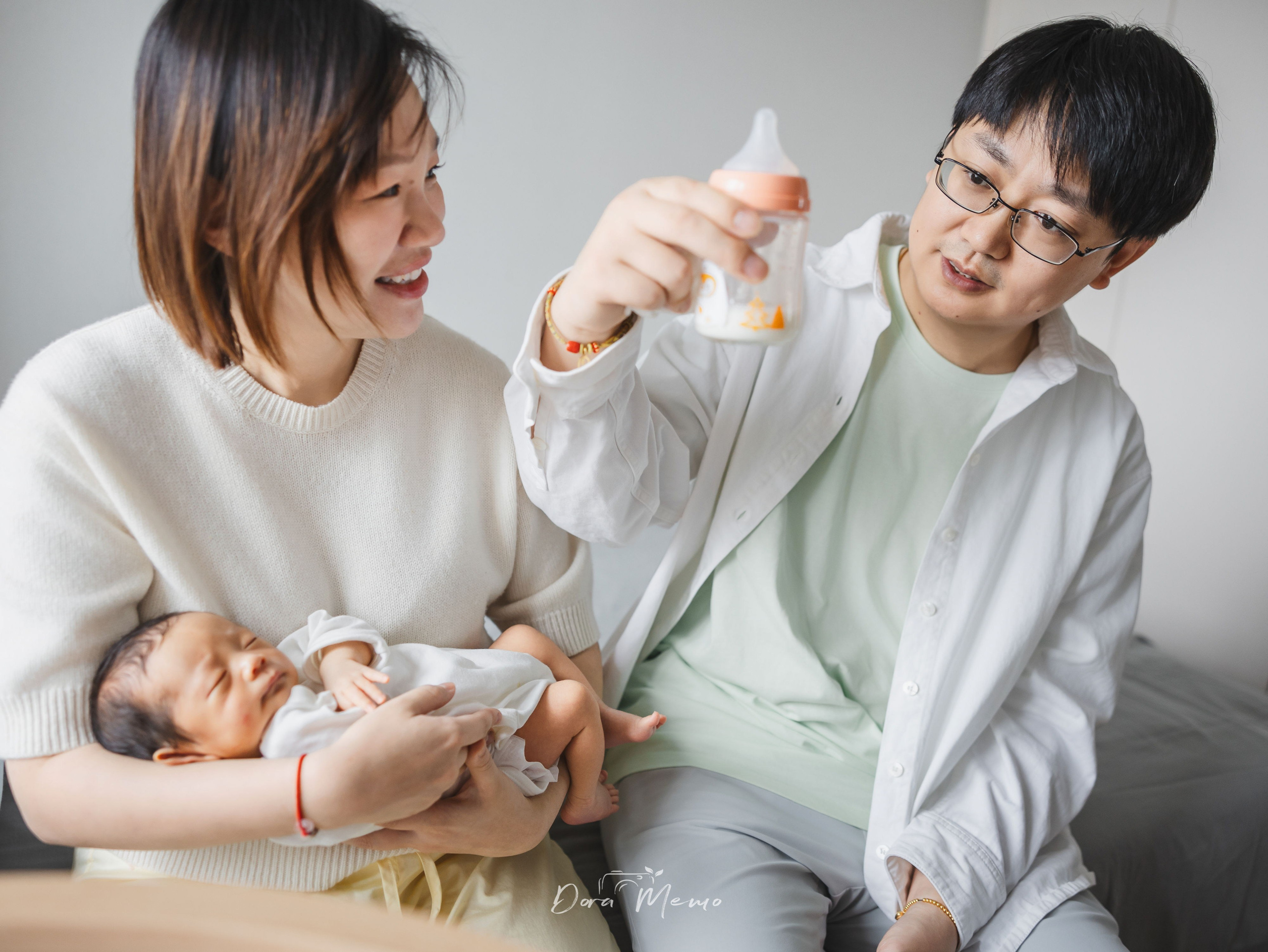 Father and mother working together to bottle-feed their newborn, teamwork in new parenthood