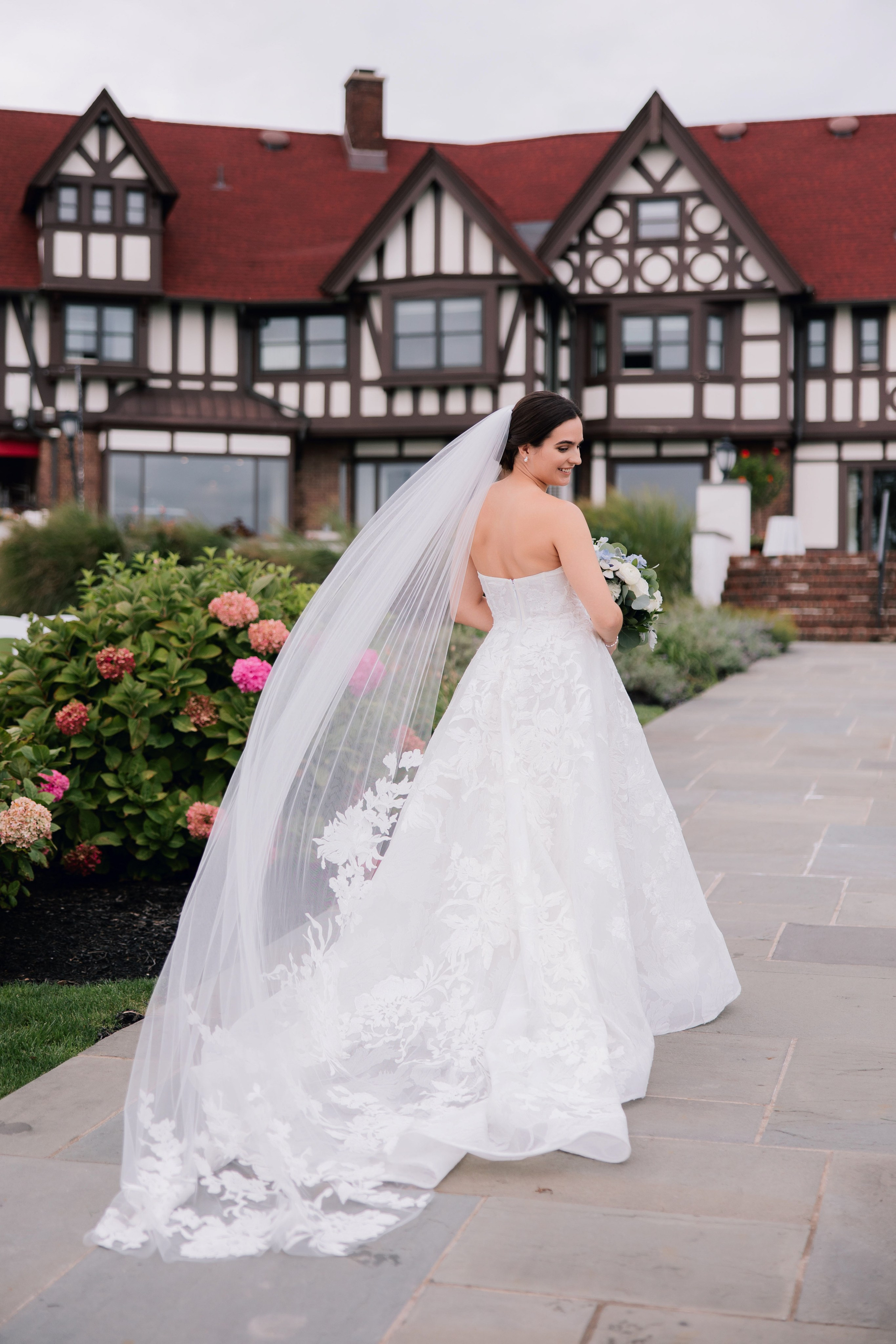 a bride in a wedding dress and veil walking down the sidewalk