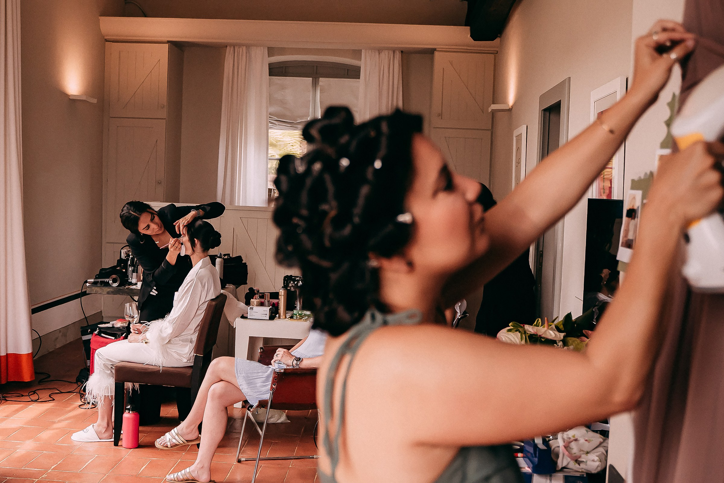 A lively bridal suite filled with stylists, laughter, and anticipation as final touches are added for the big day.