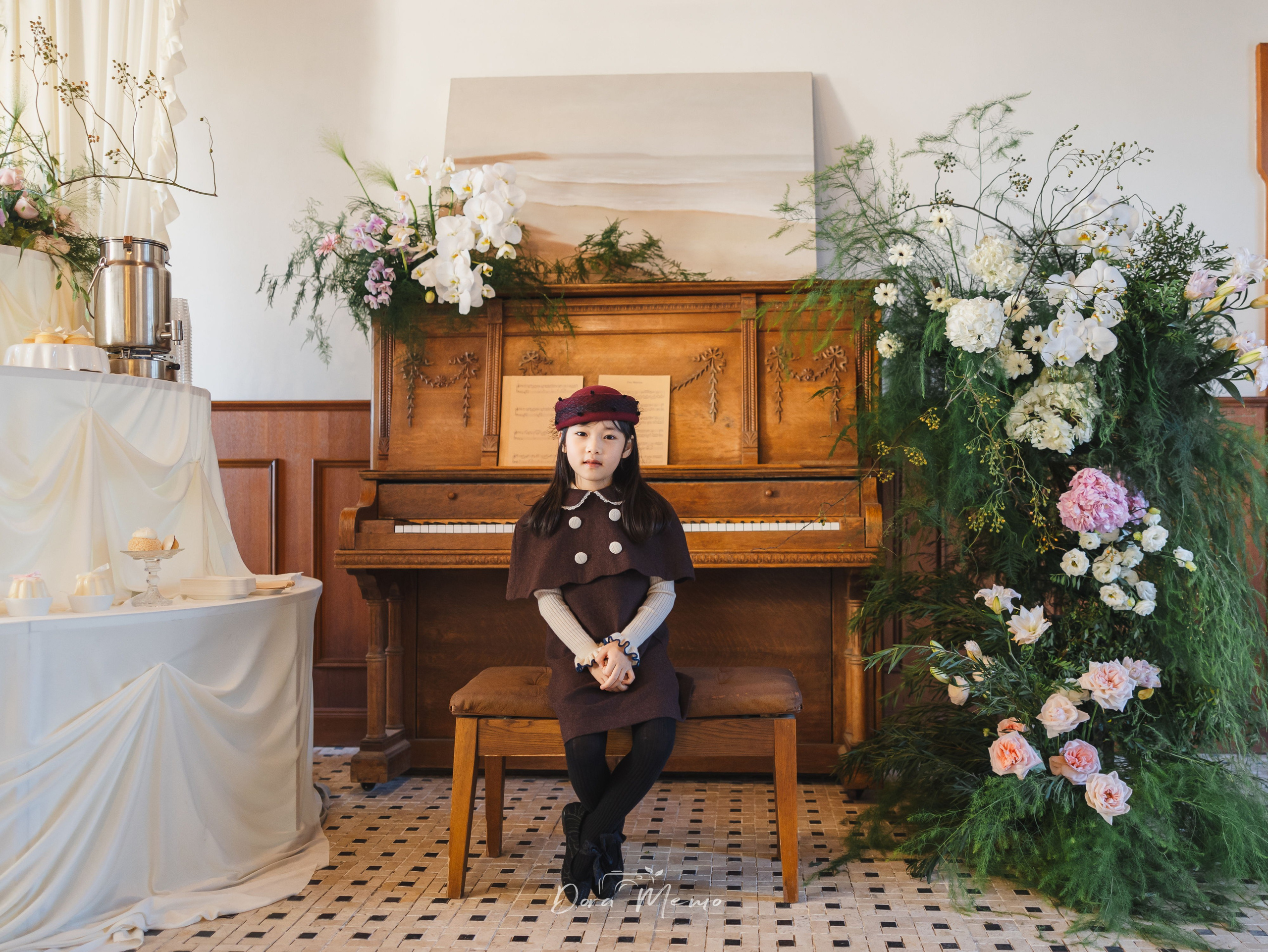 Child sitting at piano with hands folded, intimate indoor moment during birthday celebration