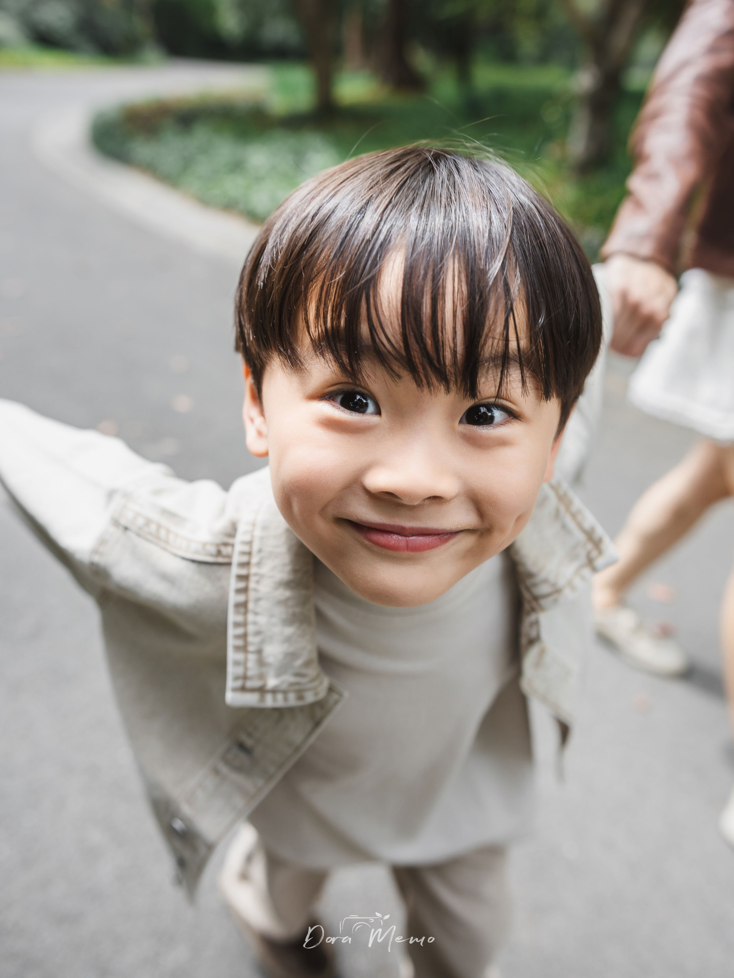 A boy held between his parents' hands looks up laughing, pure joy on his face