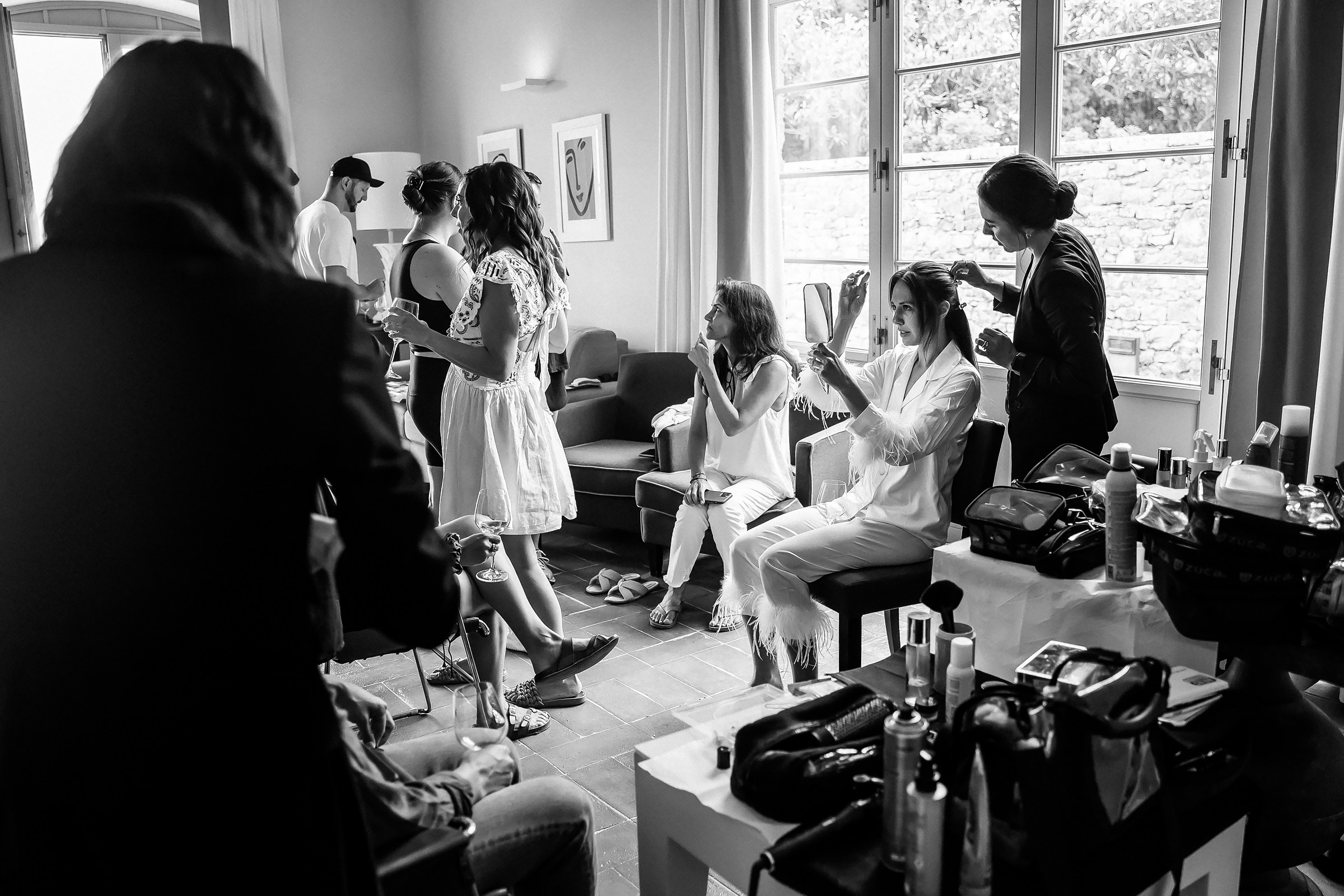 A lively bridal prep scene, featuring hair stylists, bridesmaids, and an air of joyful anticipation in Tuscany.