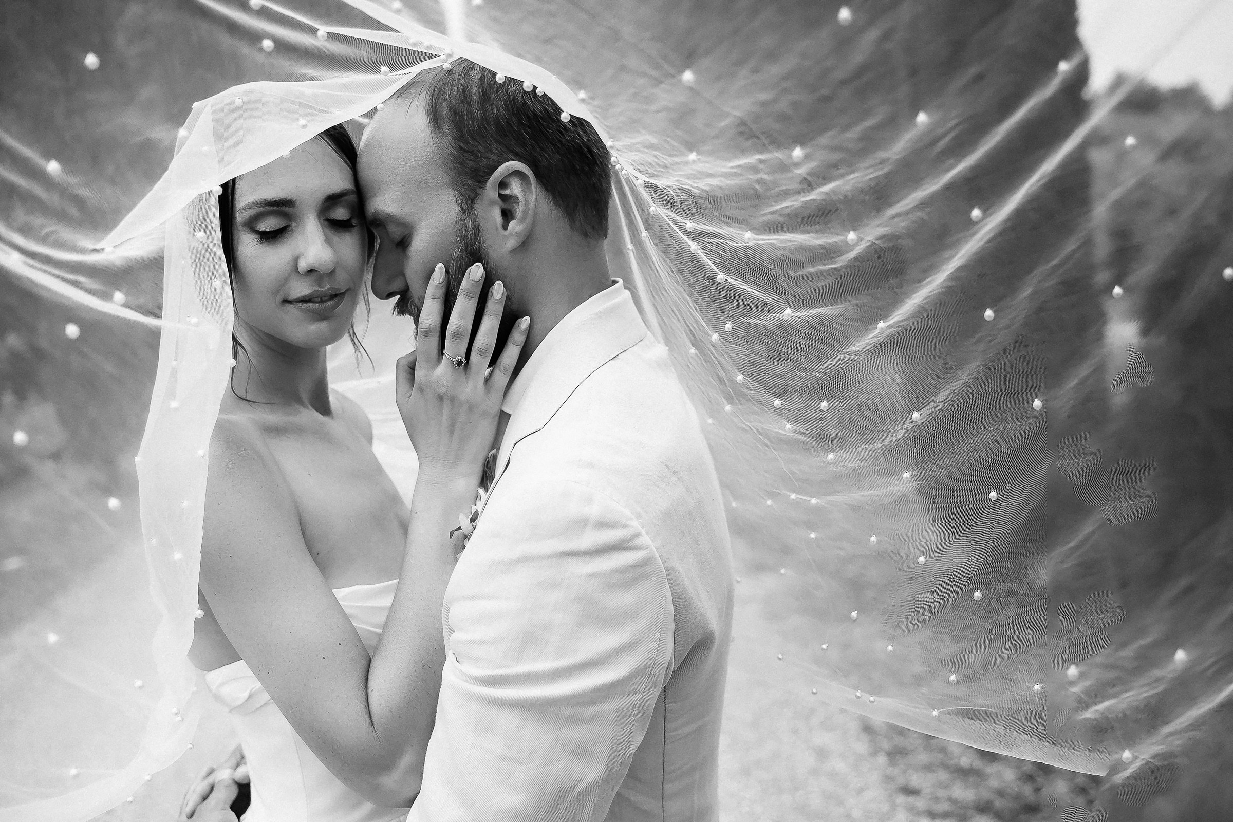 Romantic veil-draped black-and-white portrait of the couple, an intimate embrace.