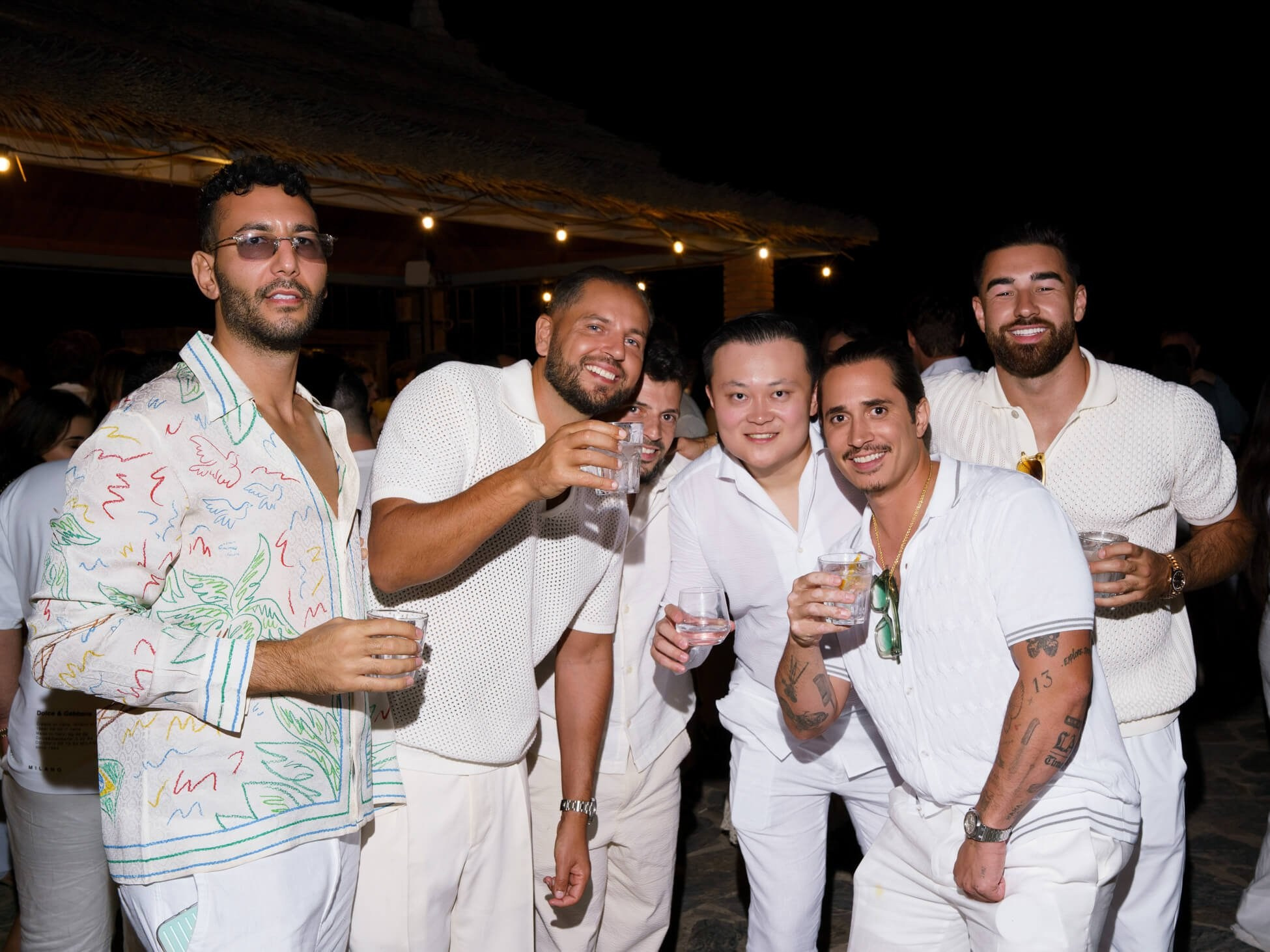 Group of guests holding drinks at luxury desert wedding party, Morocco