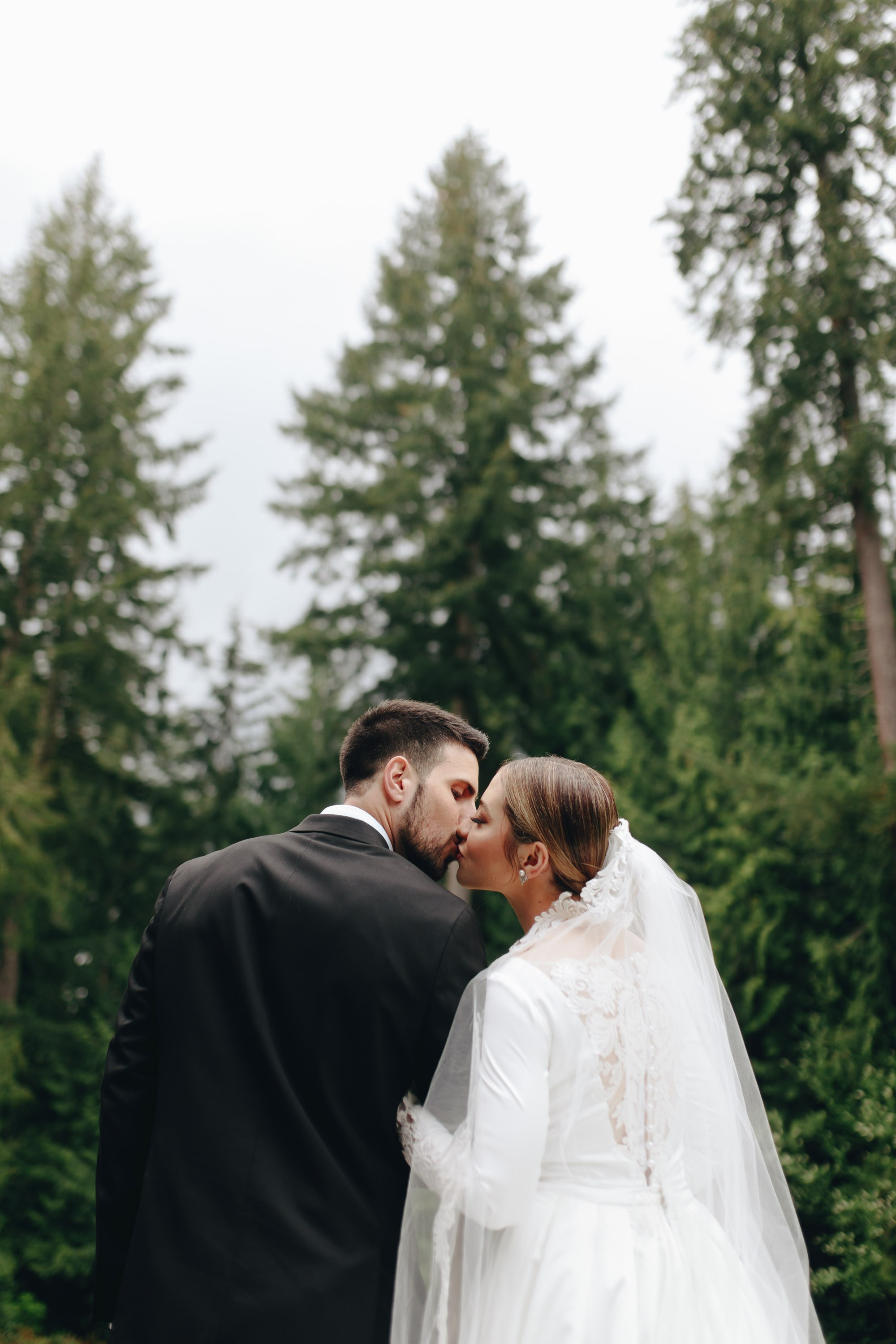 Bride and groom kissing in forest, wedding day
