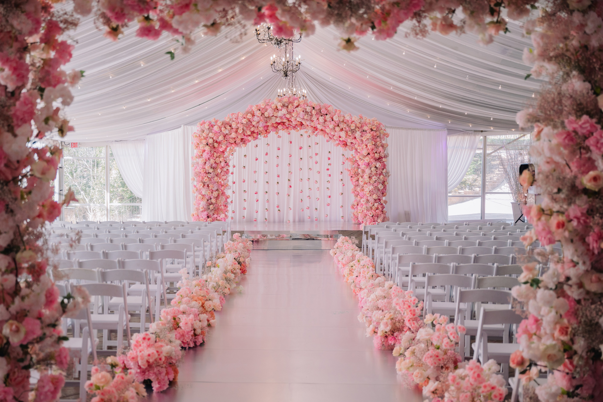 a wedding ceremony with pink flowers and white chairs