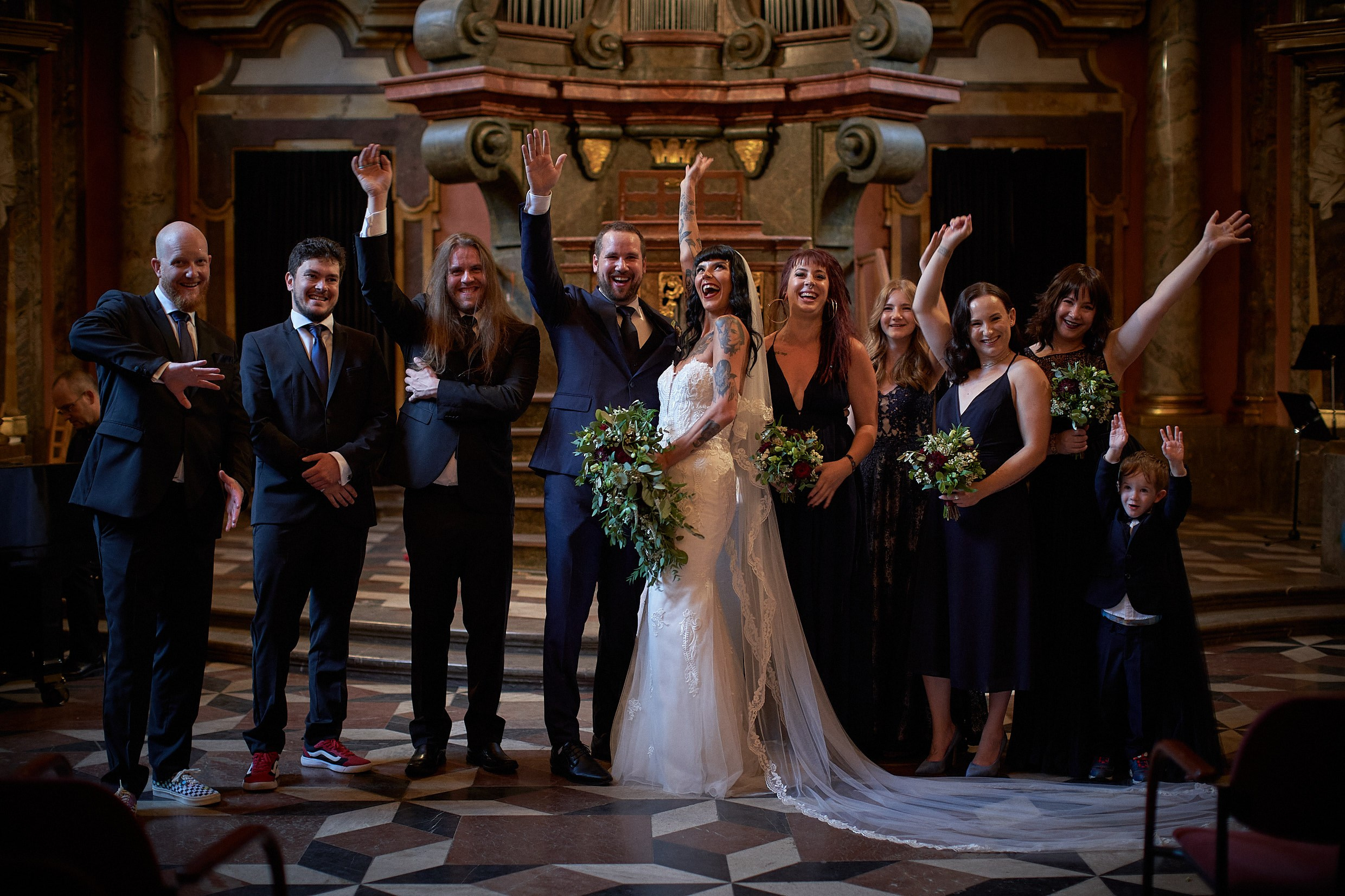 Wedding party group photo inside ornate Klementinum Mirror Chapel.