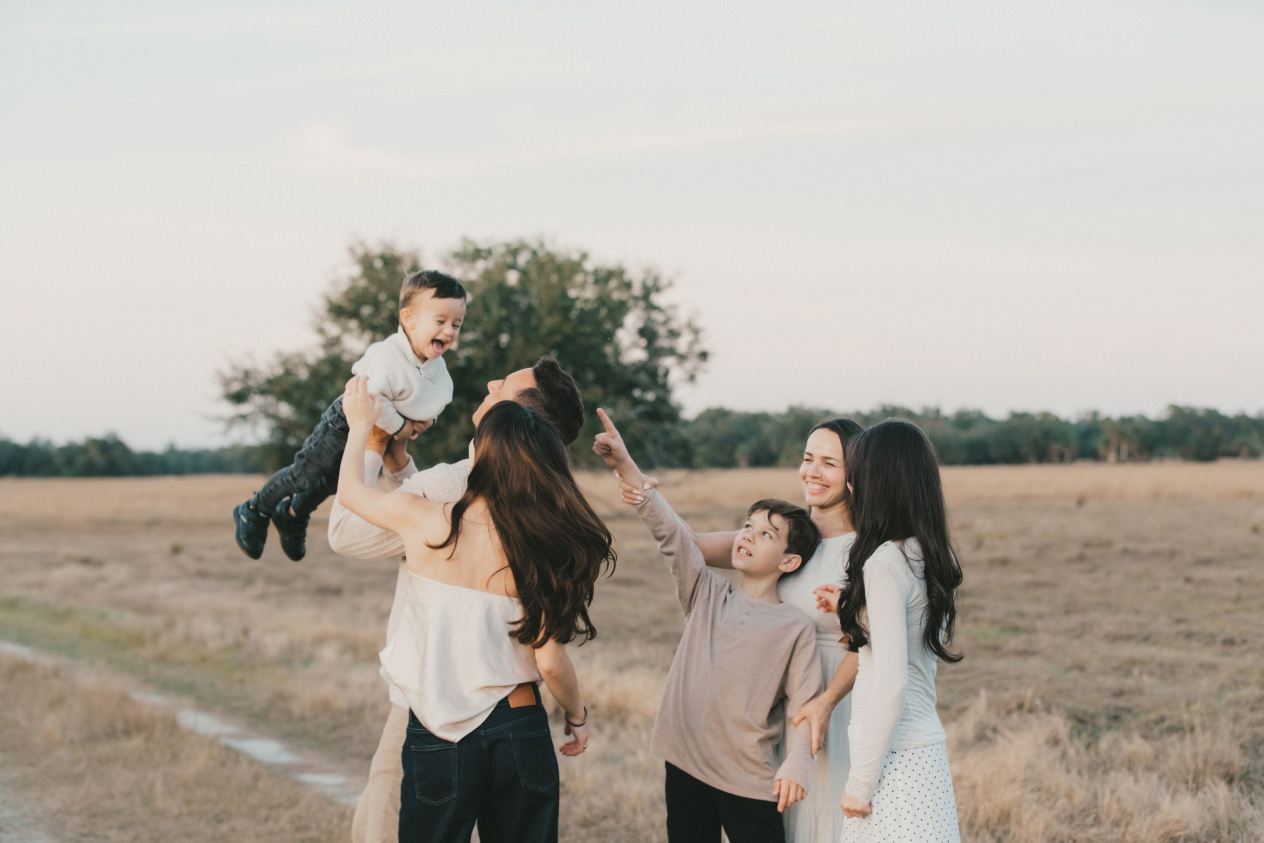 Father lifting his toddler son in the air, sunset light, joyful family session at walton ranch