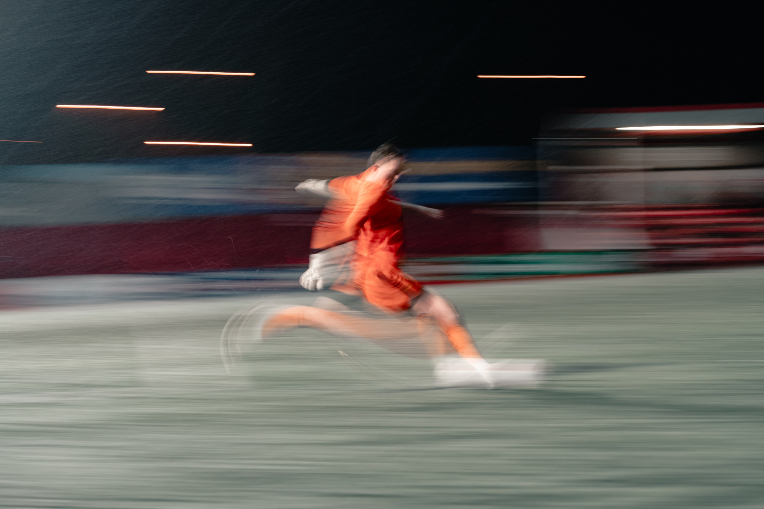 Football player sprinting during a night match with motion blur, dynamic action football photography