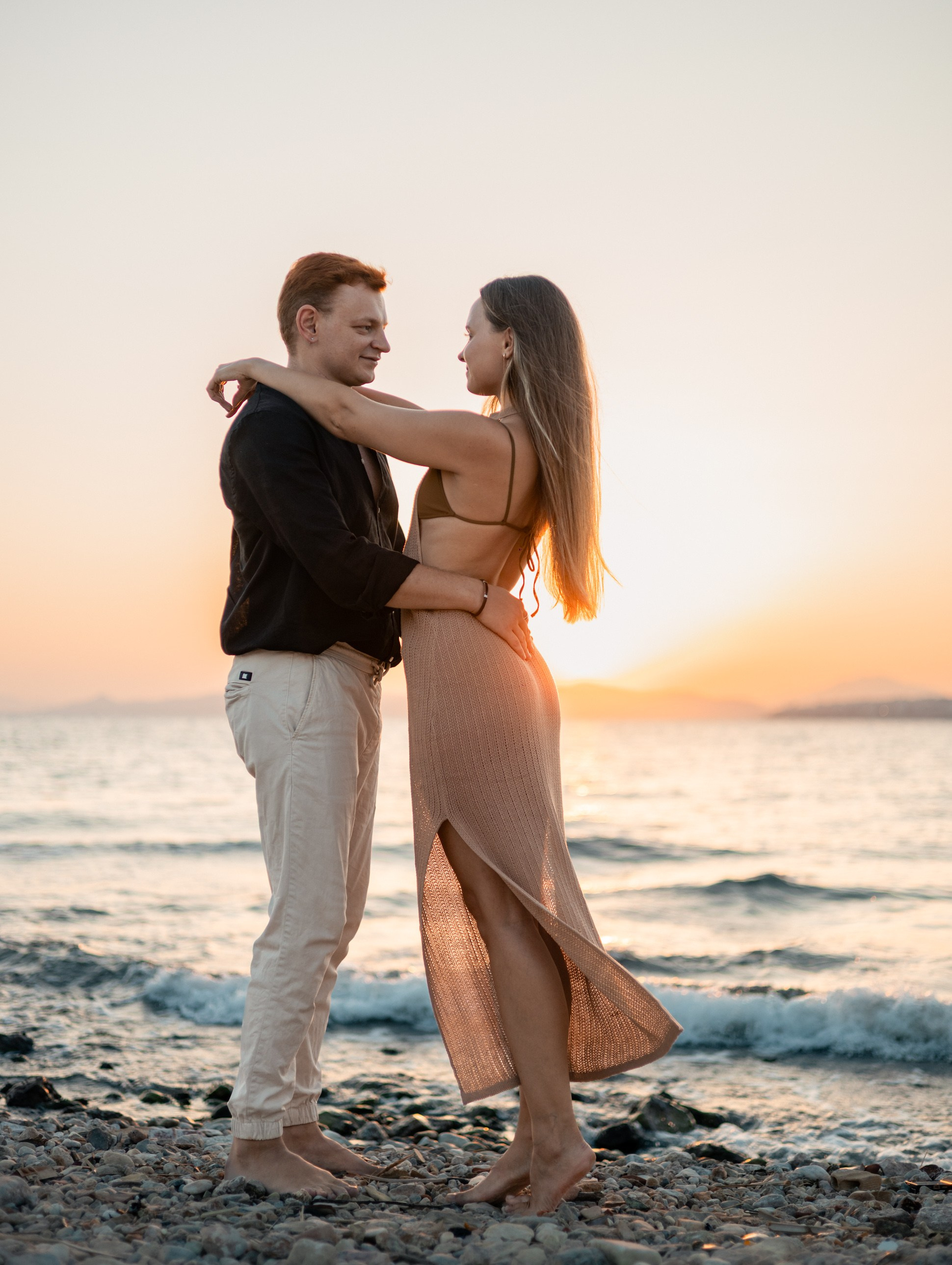 Couple embracing during a sunset beach photoshoot