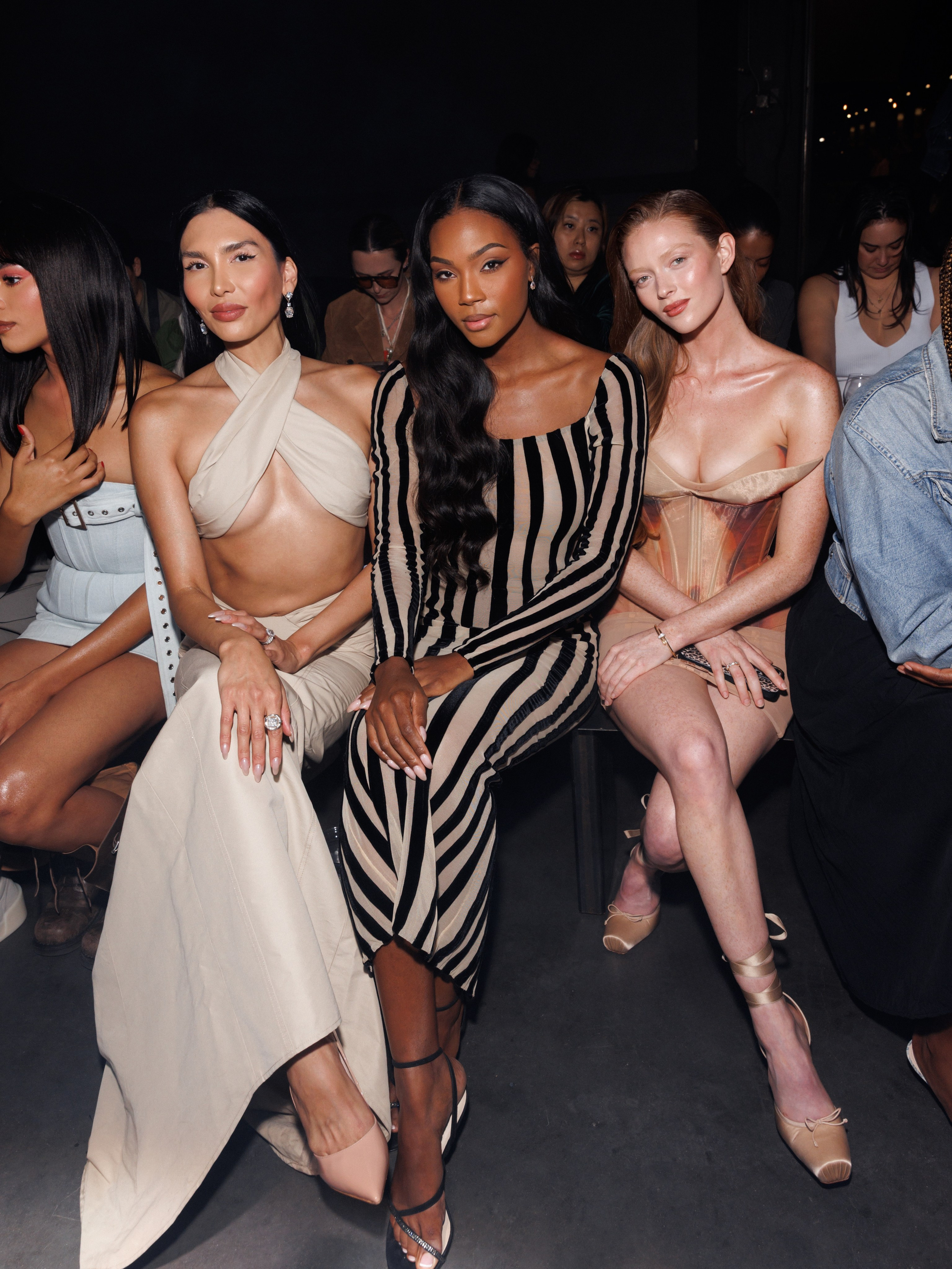 Model in sheer black dress watching runway – editorial event photo