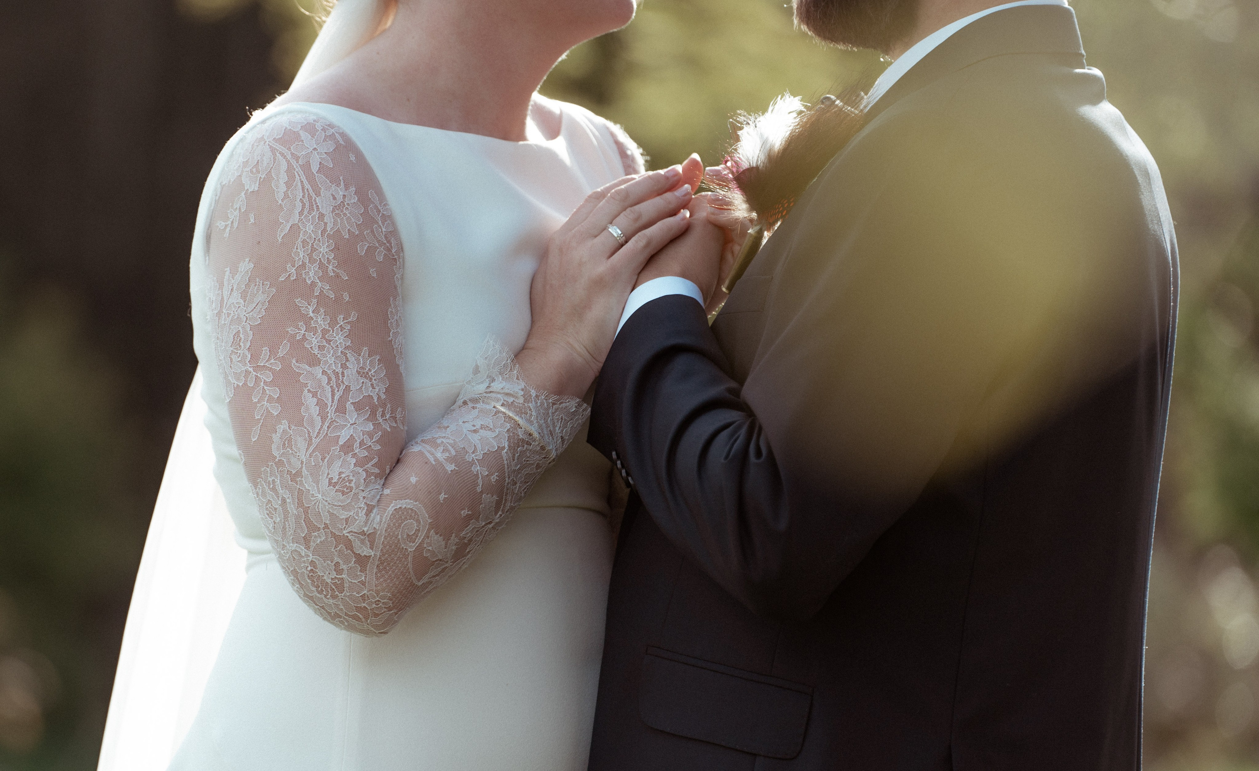 Brudens hånd med vielsesringen på brudgommens skulder