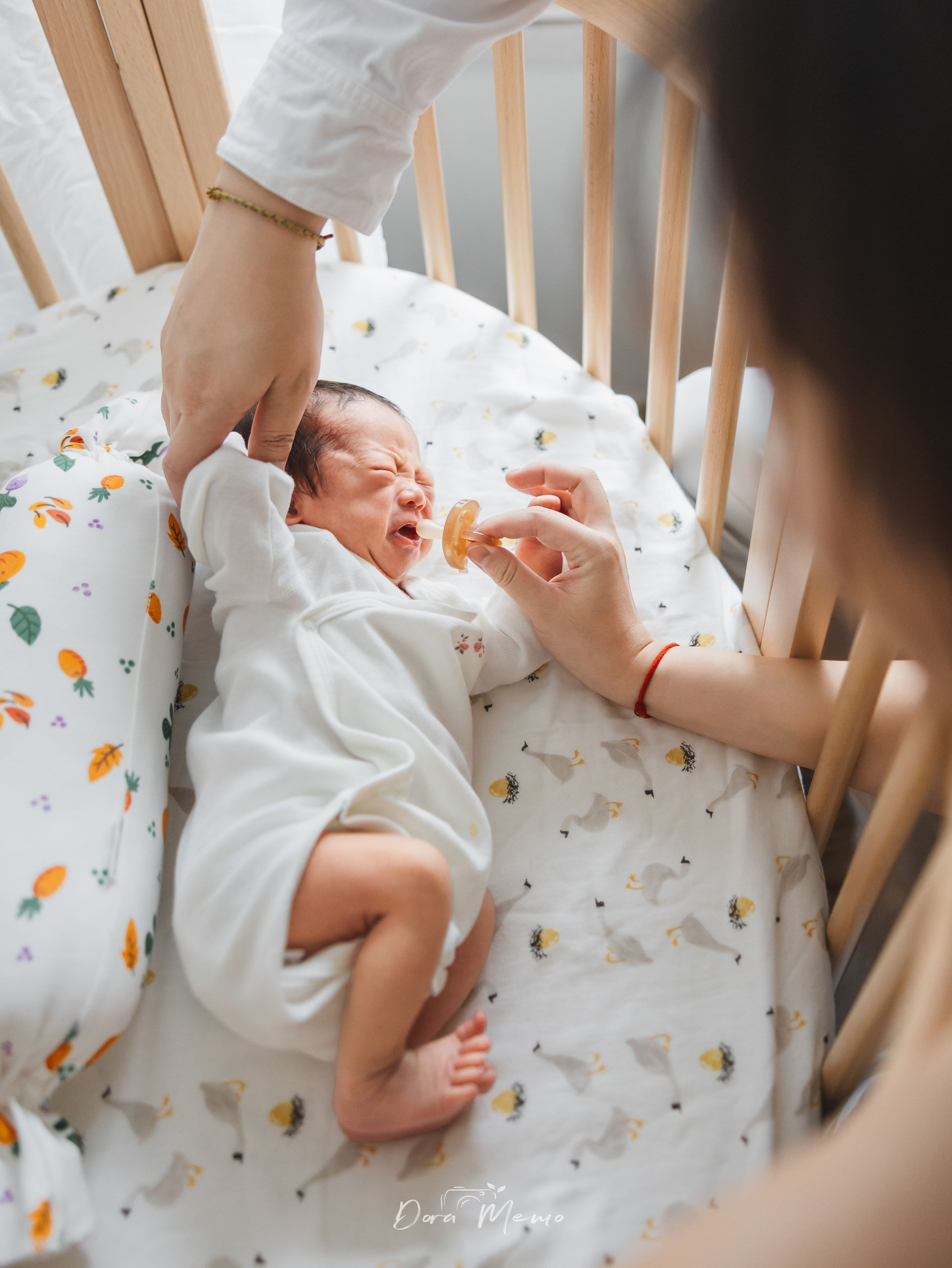 Mother comforting her crying newborn with a pacifier, honest moment of new parenthood