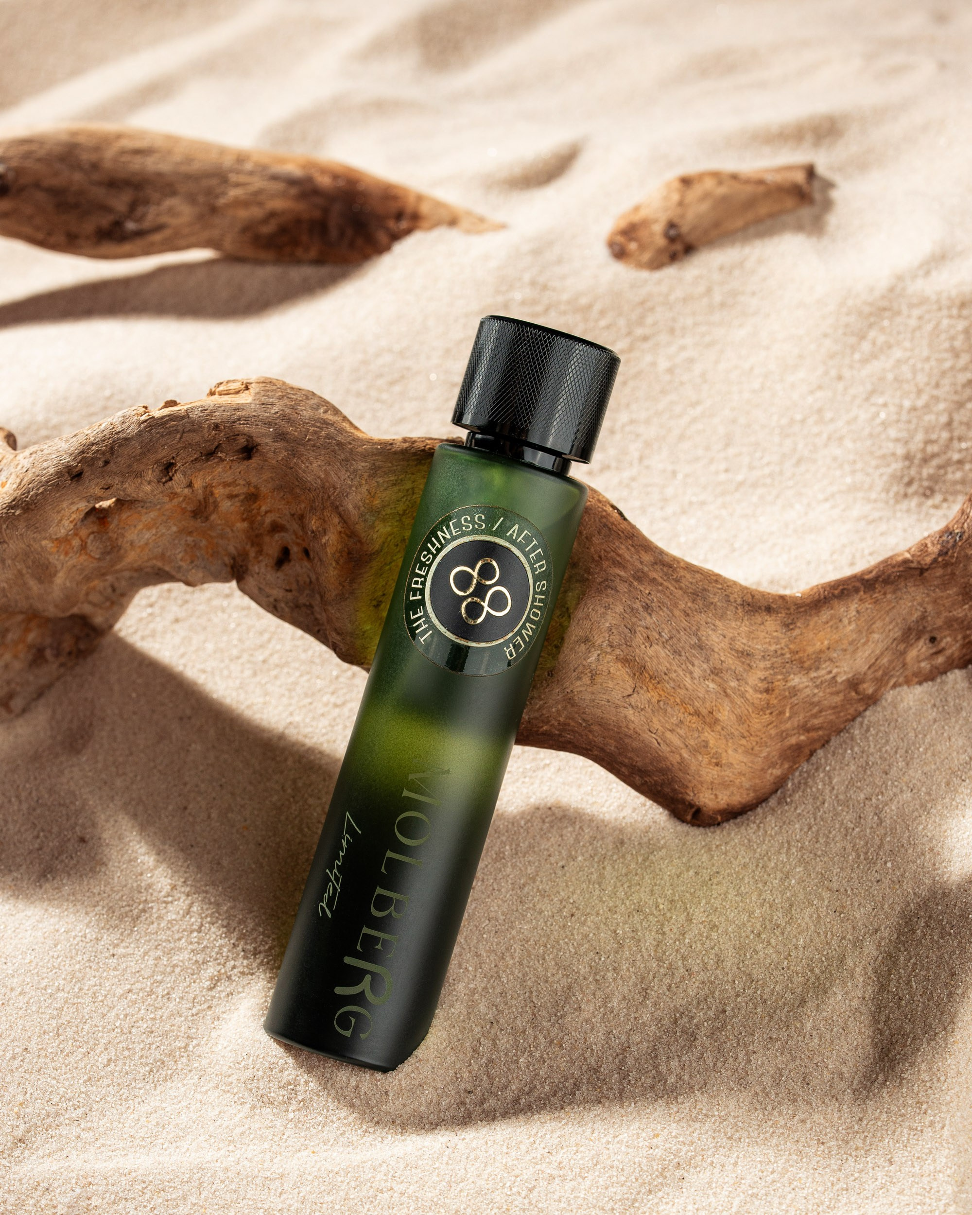 Qara qapaqlı, yaşıl rəng çalarlı "MOLBERG" xəttindən ("Lustful" etiketli) olan ətir şüşəsi, qurumuş ağac parçasına söykənərək açıq rəngli təbii qum üzərində yerləşdirilib. Səhnə təmiz, təbii görünüşü vurğulayan isti, təbii işıqlandırma ilə çəkilib.