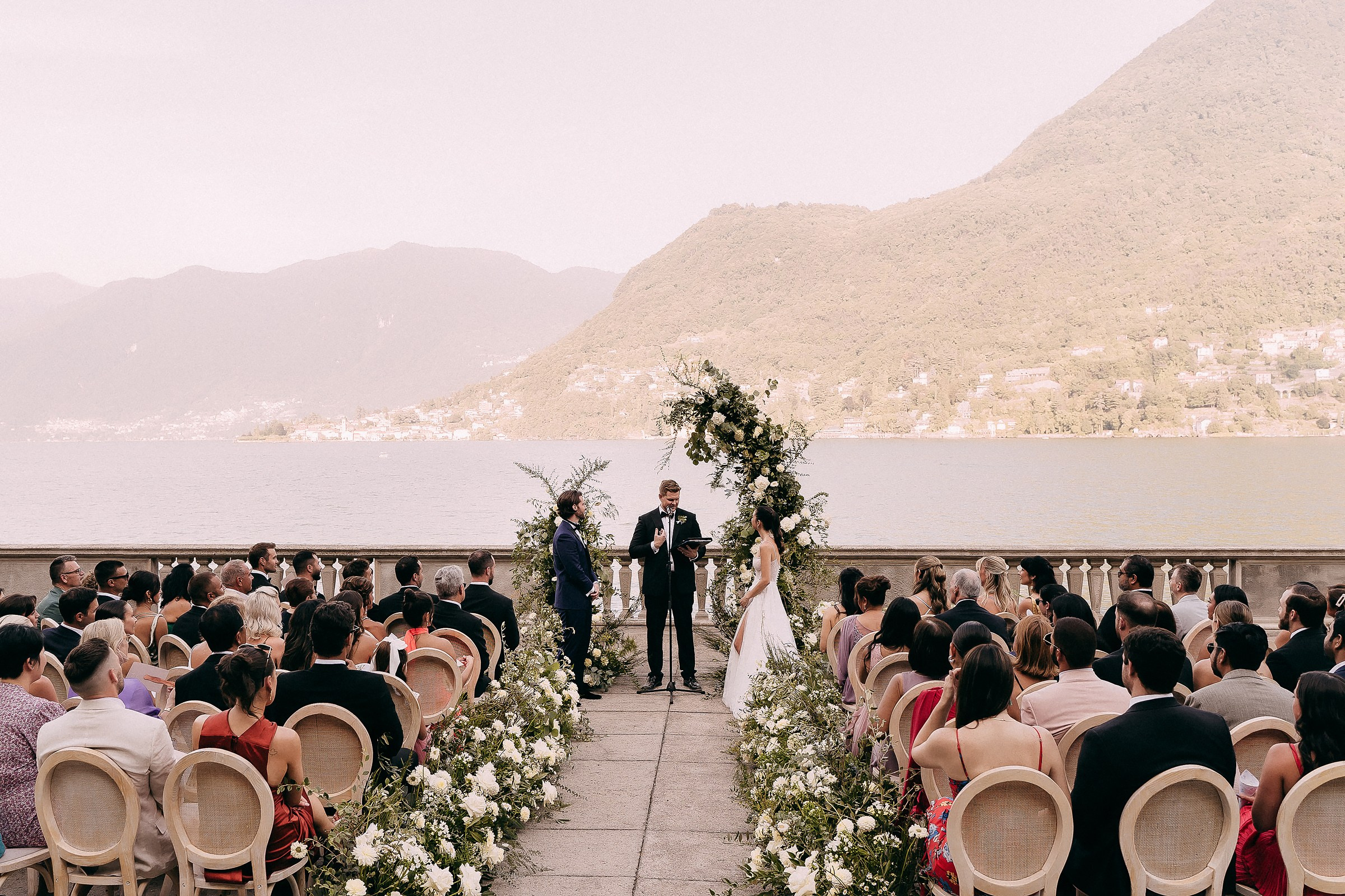 An enchanting wedding ceremony on the shores of Lake Como, with guests gathered amidst breathtaking natural scenery.