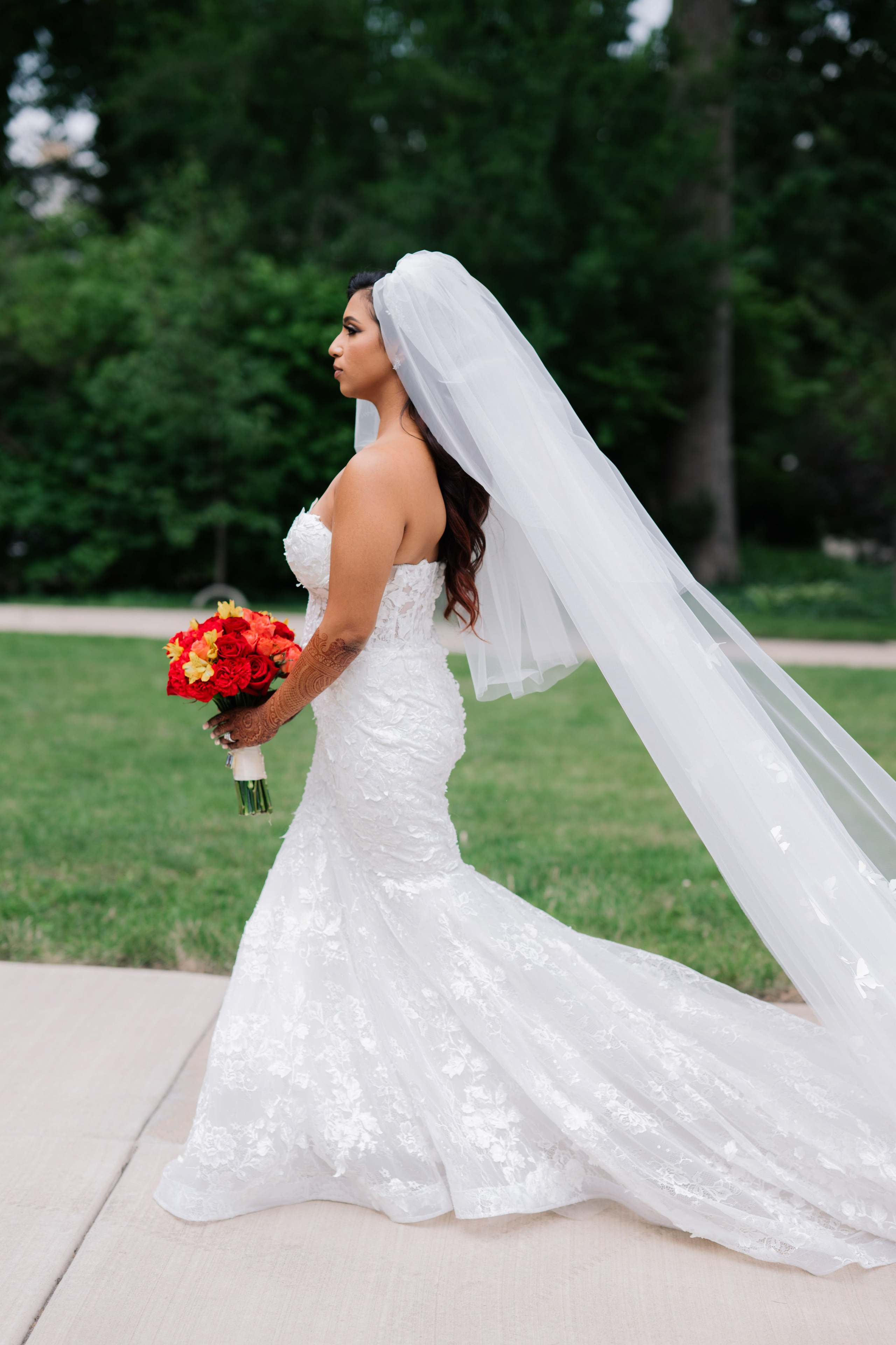 a bride in a wedding dress and veil walking down the sidewalk