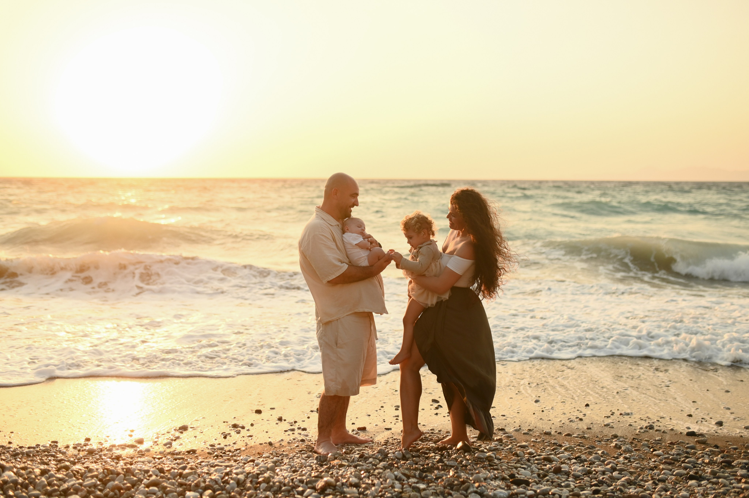 Happy family walking along a Rhodes beach at sunset. Photographer in Rhodes Island